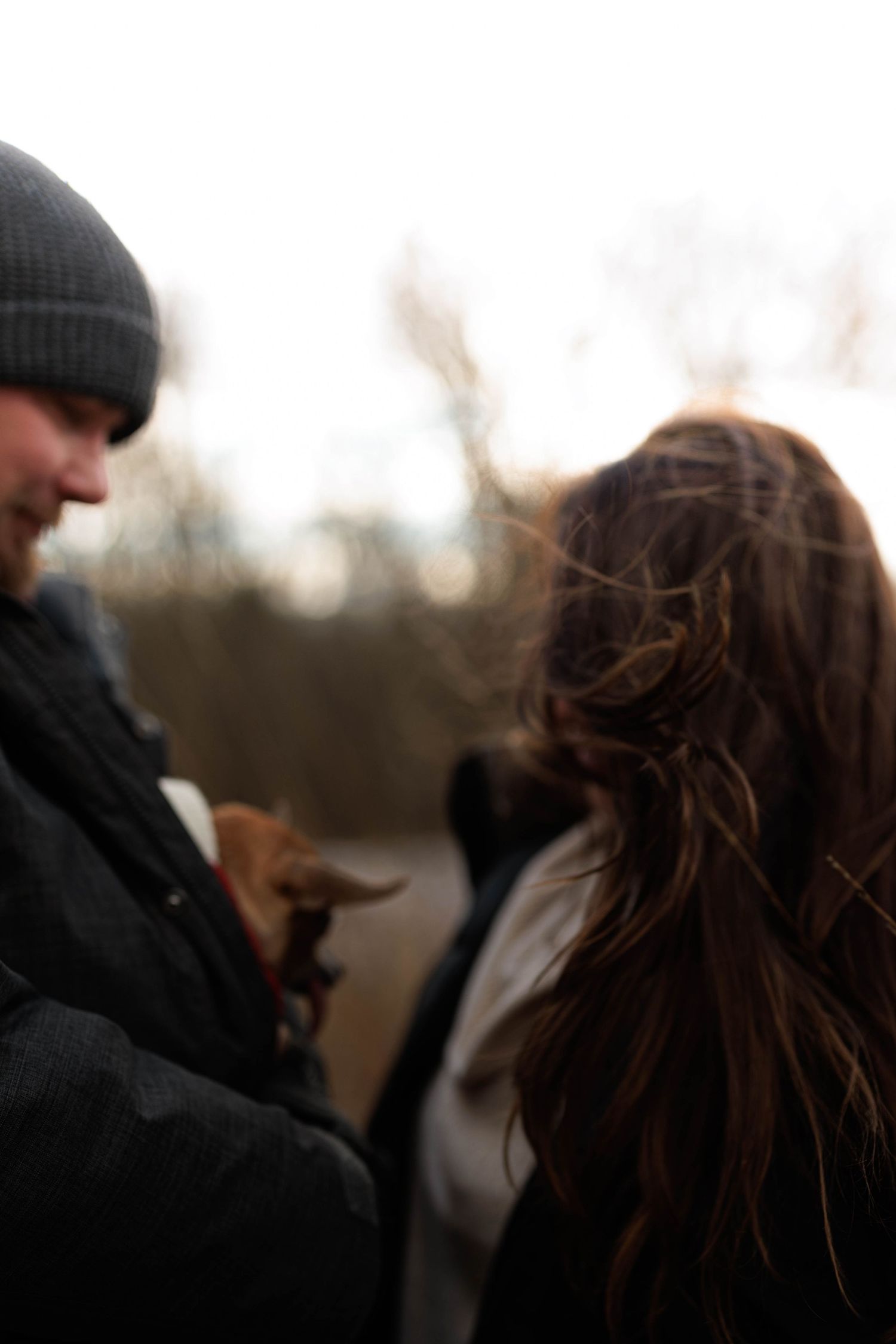 A couple shares an intimate moment outdoors with their faces close together in a romantic pose.
