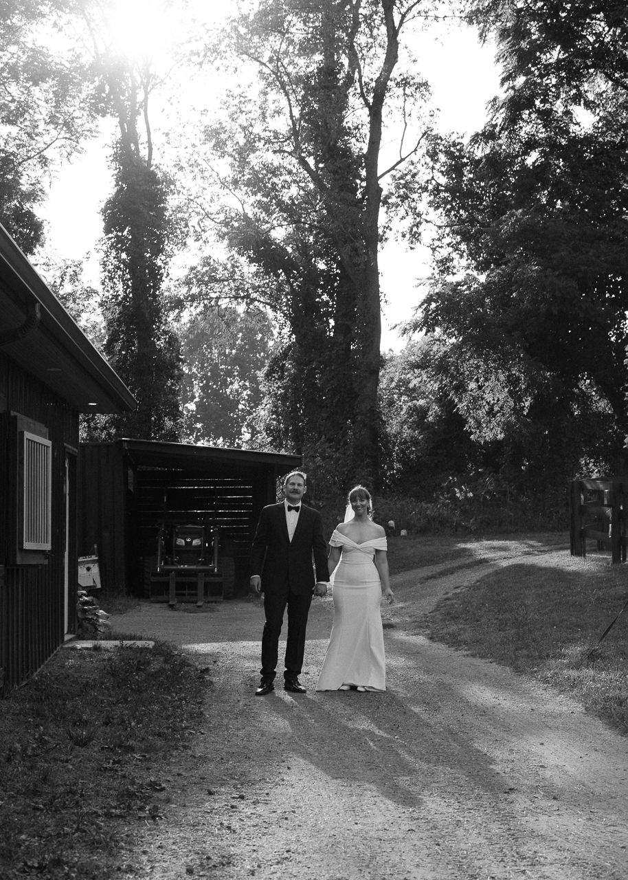 A couple walks along a tree-lined country path during a wedding ceremony.
