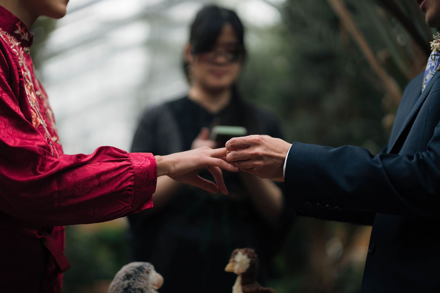 Couple exchanges rings during intimate wedding ceremony with officiant in background.