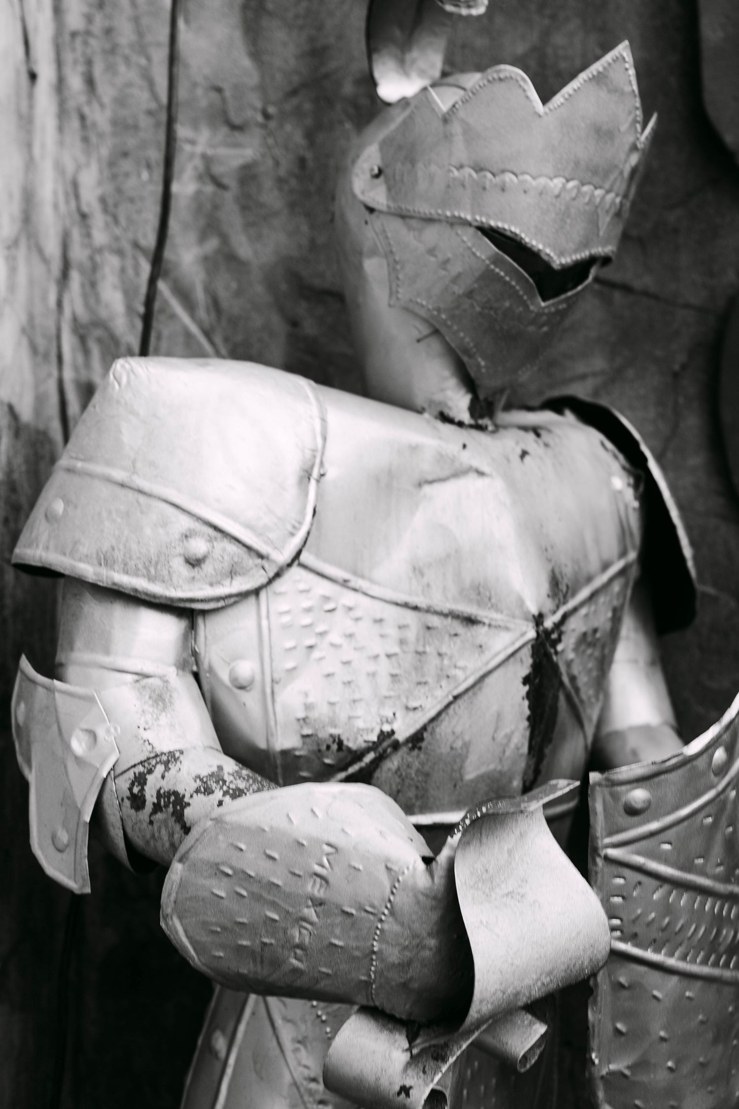 Black and white close-up of a weathered medieval knight suit of armor with ornate detailing.