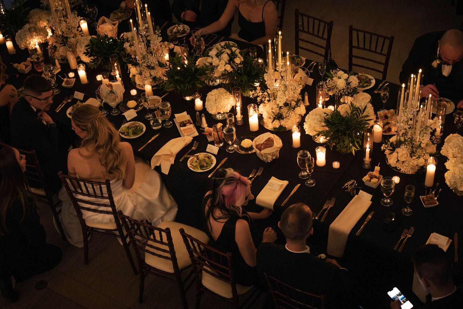 Aerial view of a luxurious candlelit wedding reception table with white floral centerpieces.