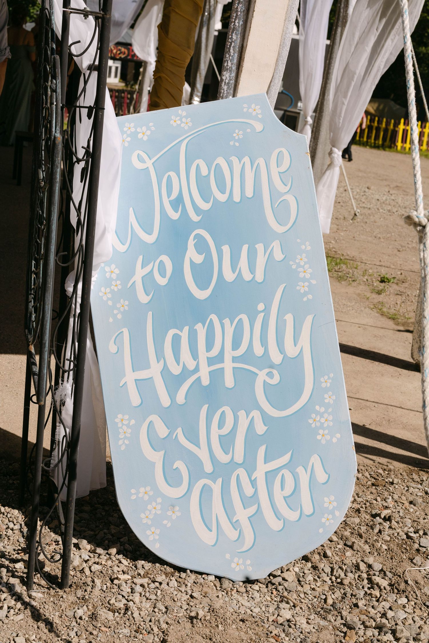 Light blue wedding welcome sign reading Welcome to Our Happily Ever After with floral details.