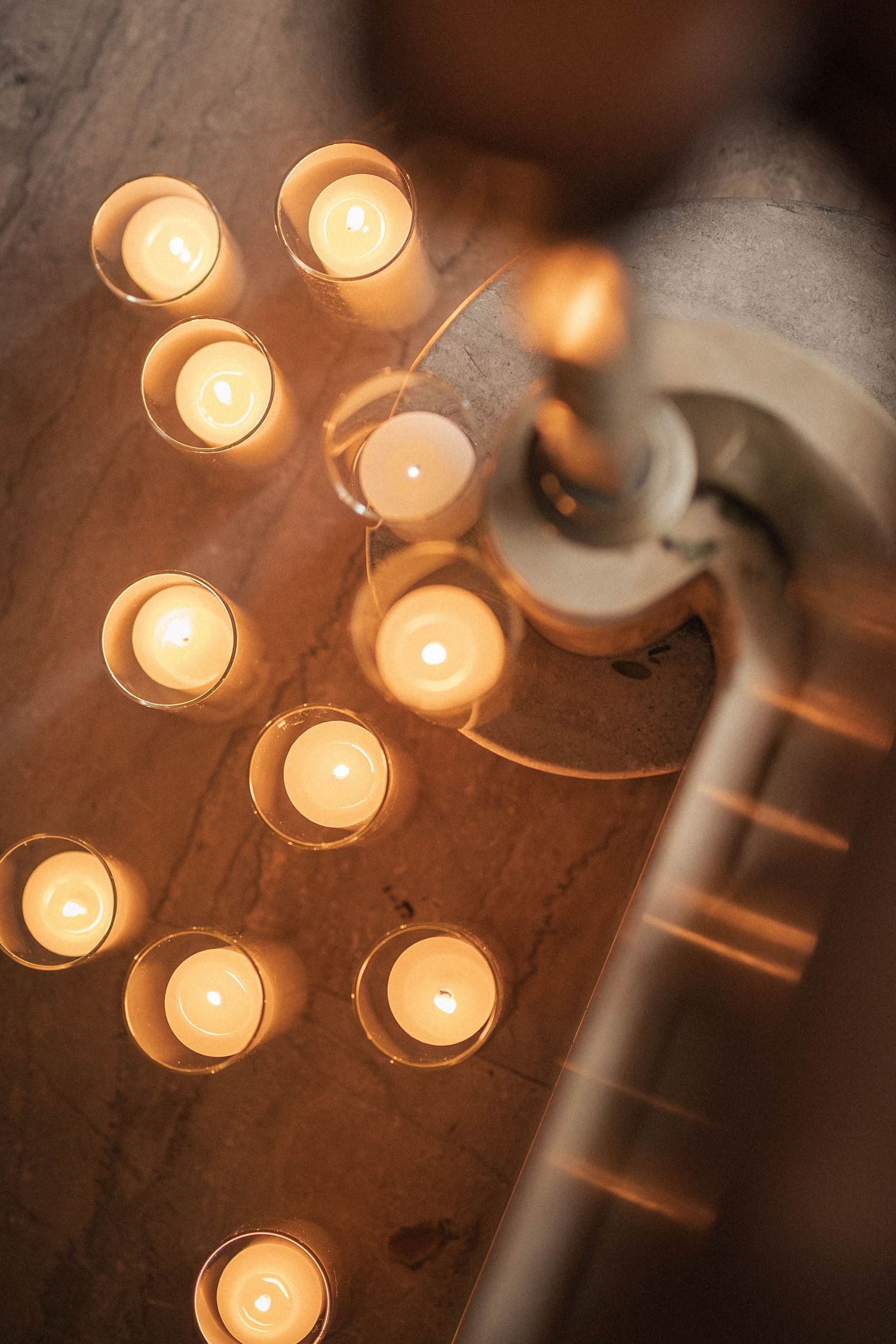 Warm glowing tea light candles arranged on marble surface with decorative candleholder at elegant event.