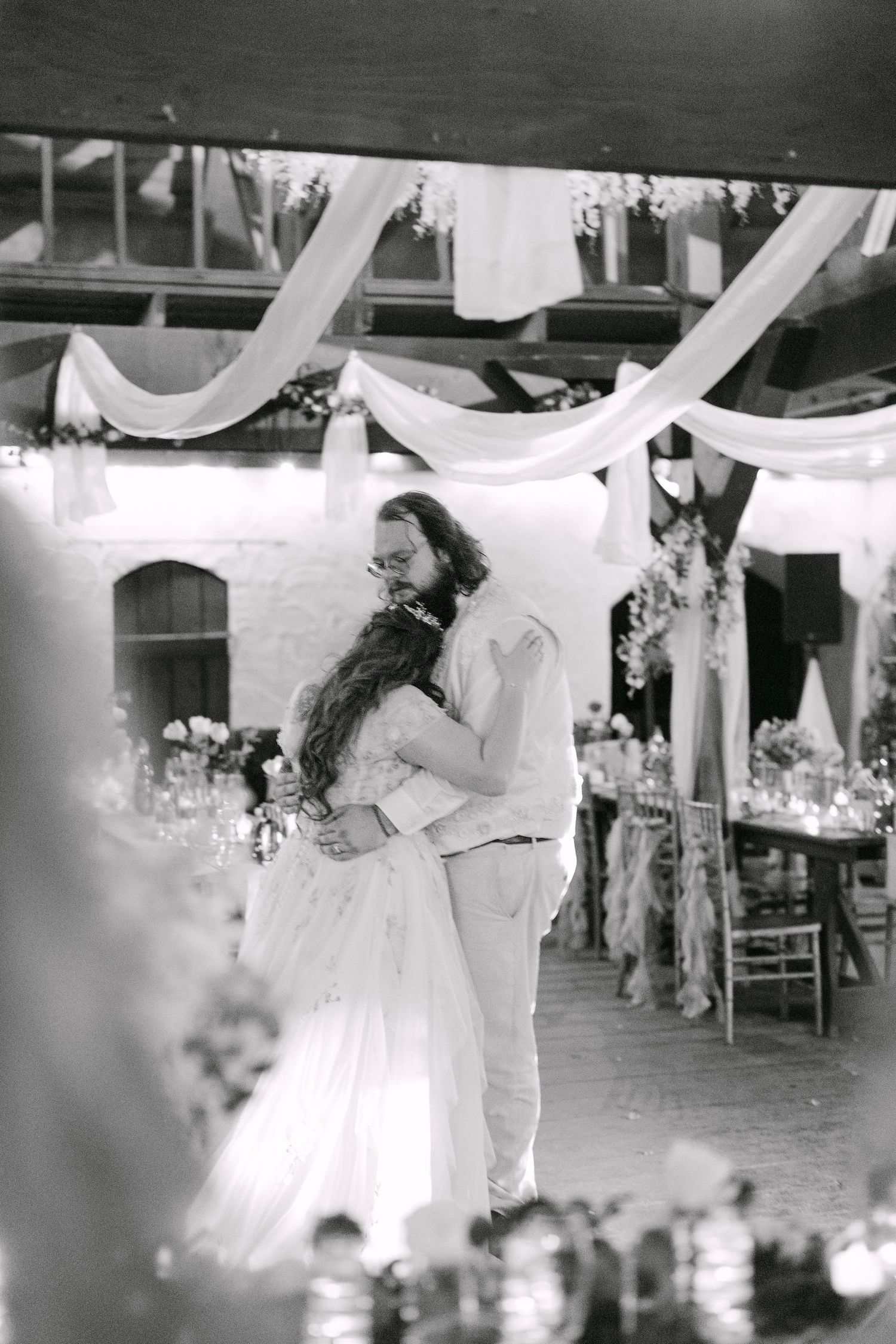 Black and white photo of bride and groom sharing first dance at elegant wedding reception.