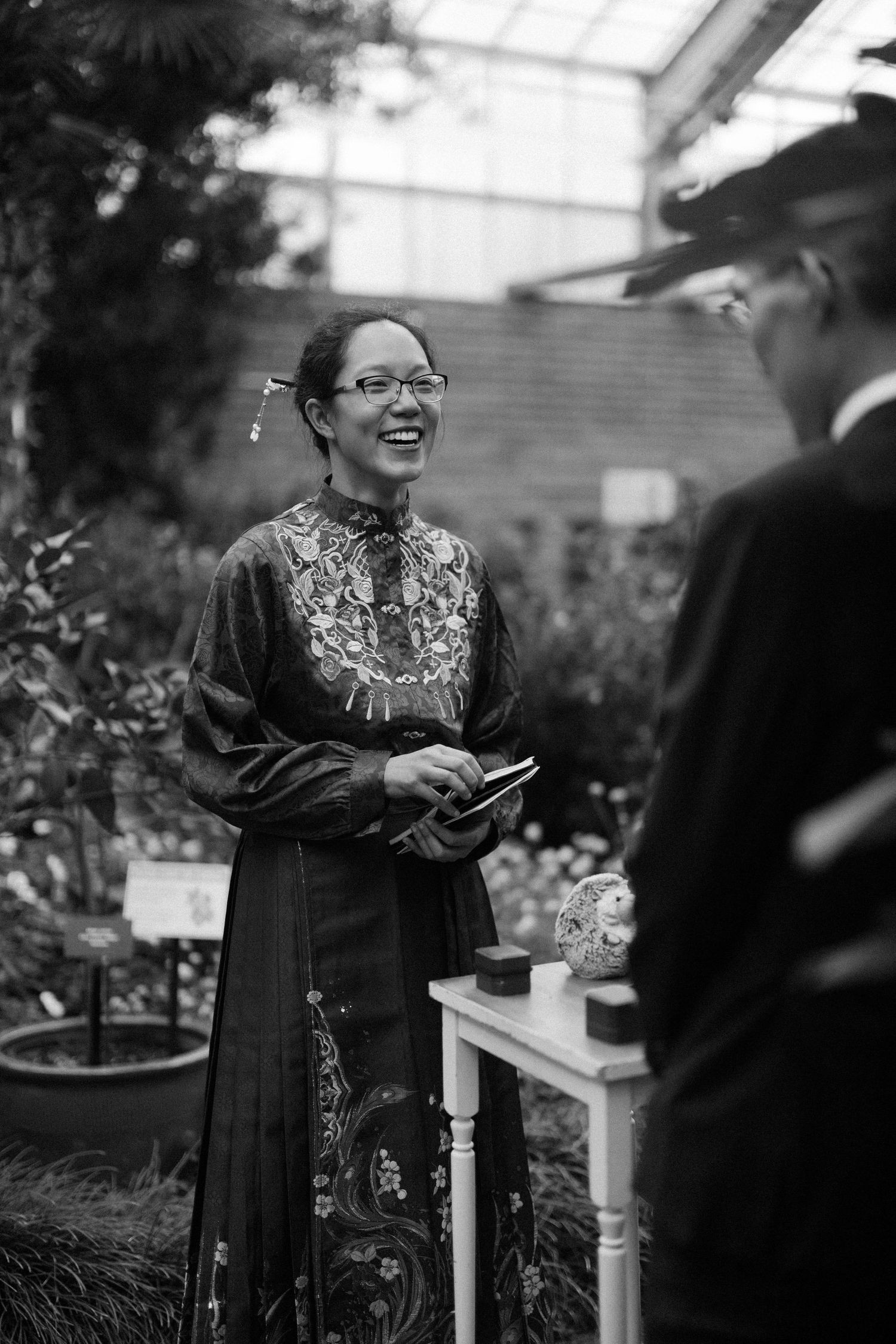 Woman in embroidered traditional Vietnamese ao dai laughing joyfully at wedding ceremony.