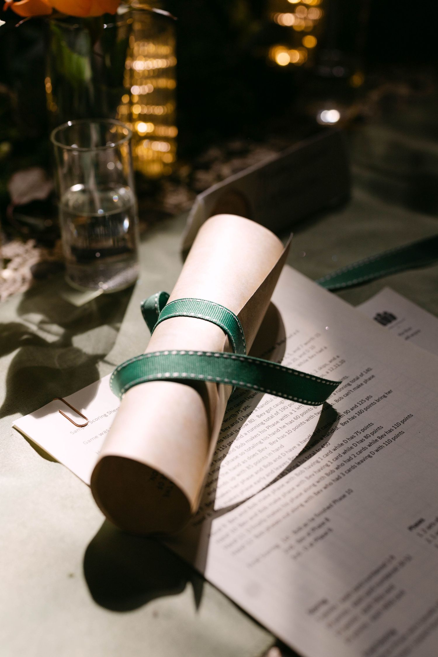 Elegant wedding scroll tied with green velvet ribbon placed beside a menu on reception table.