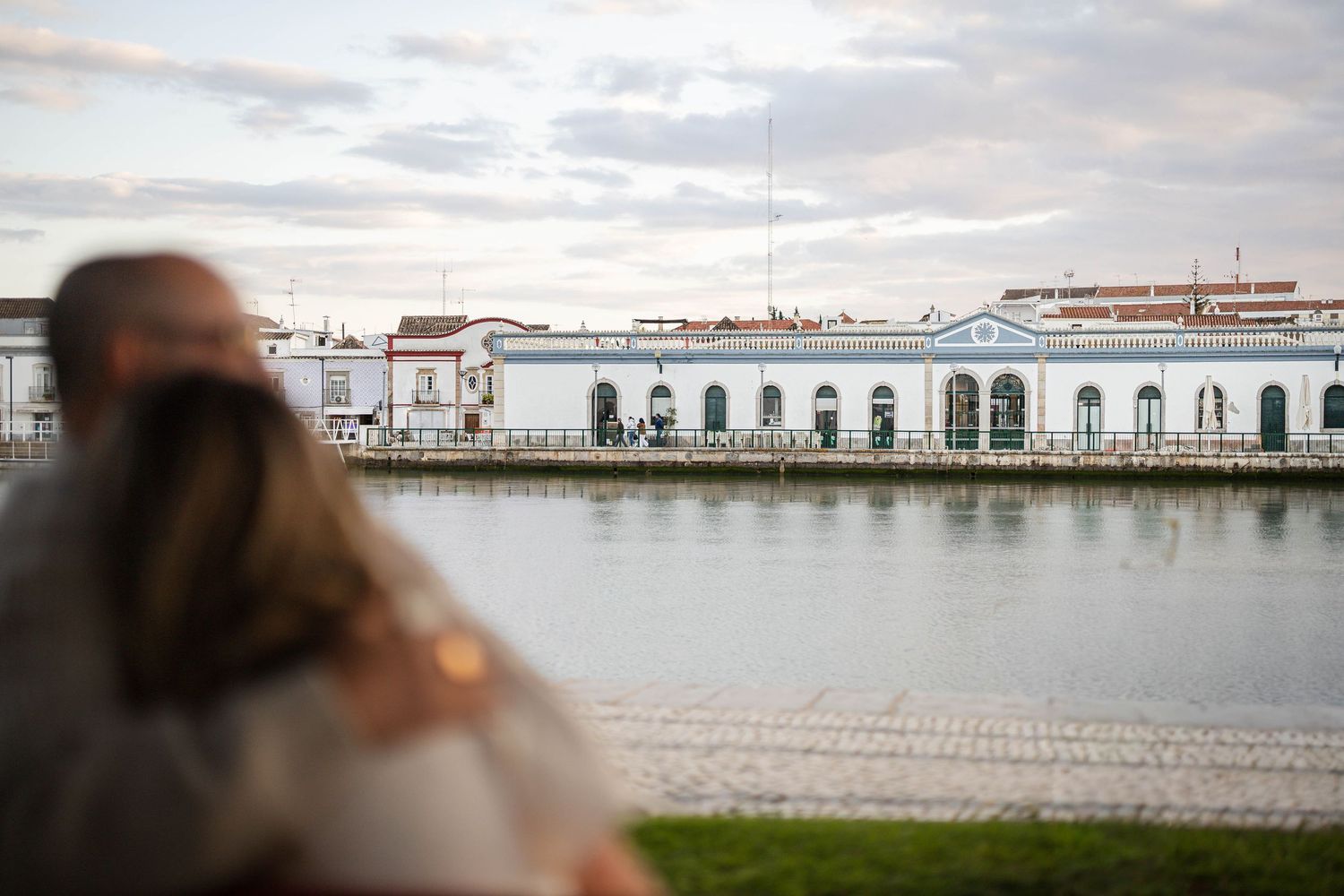 Panoramic view of a coastal city waterfront with white buildings and a calm harbor during daytime.