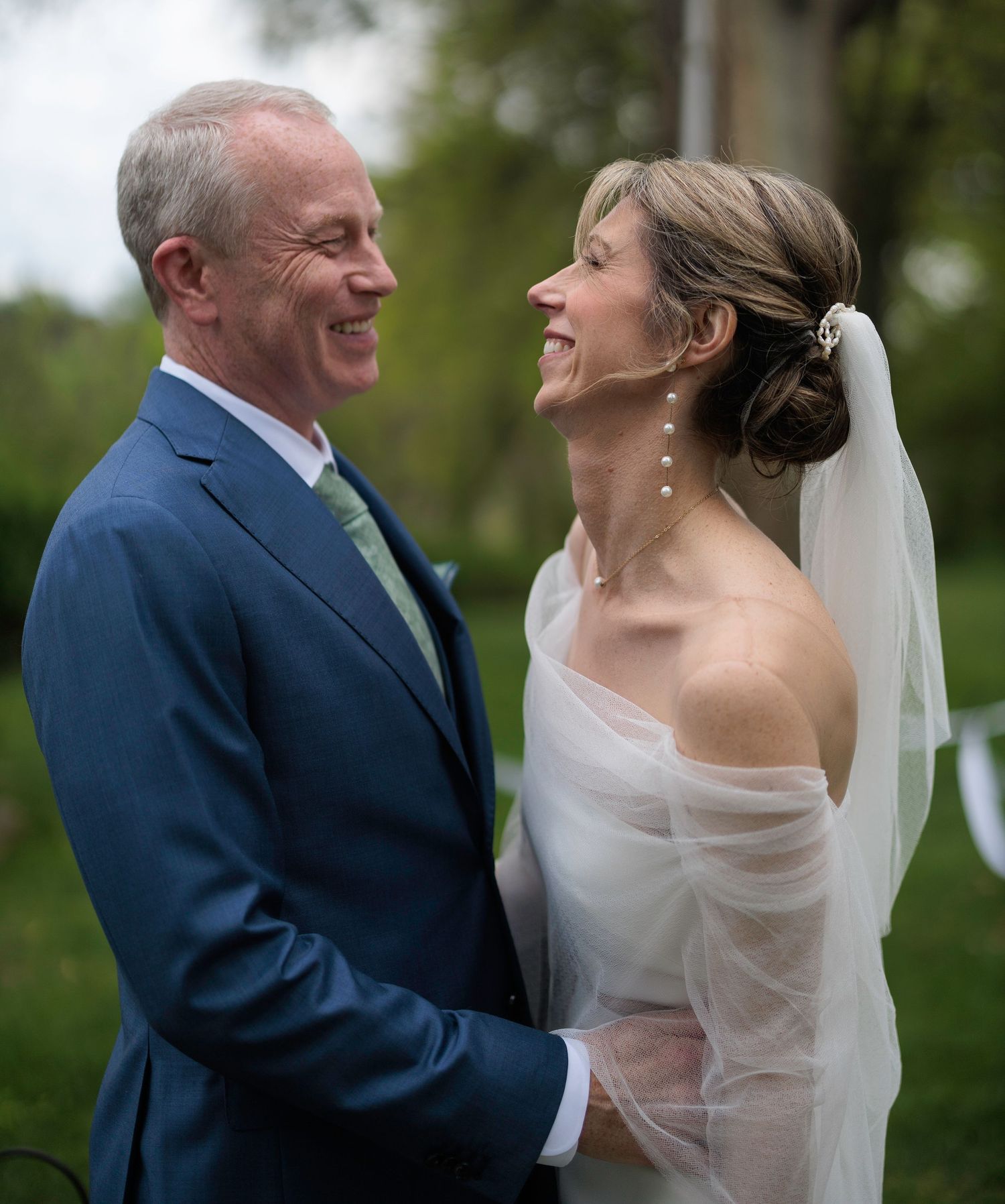Bride and groom share joyful moments outdoors in elegant wedding attire.