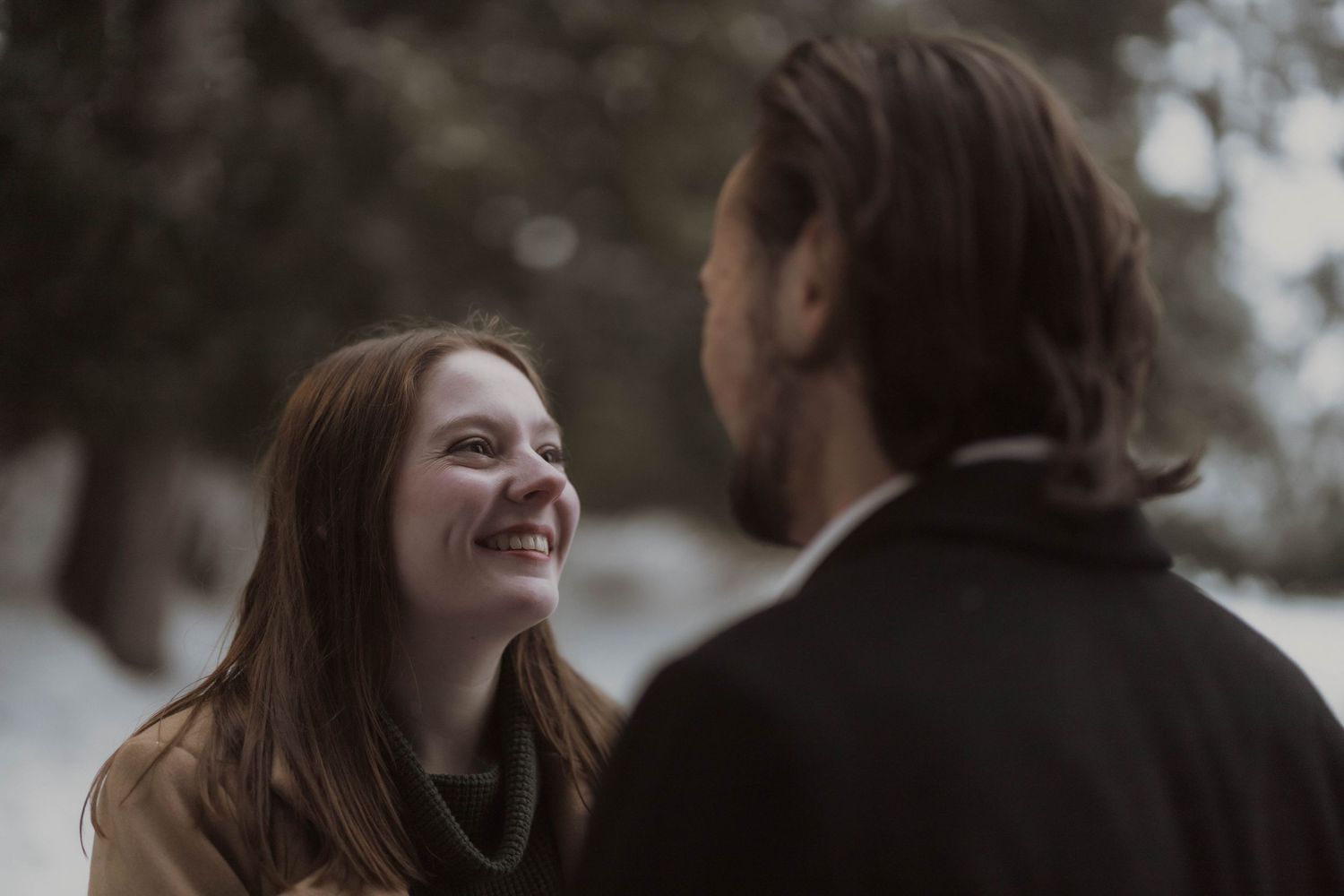 A couple shares a joyful candid moment together outdoors on an overcast day.