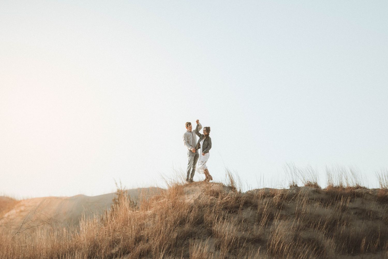 Silhouettes of people standing on a hilltop against a misty sky during sunset or sunrise.