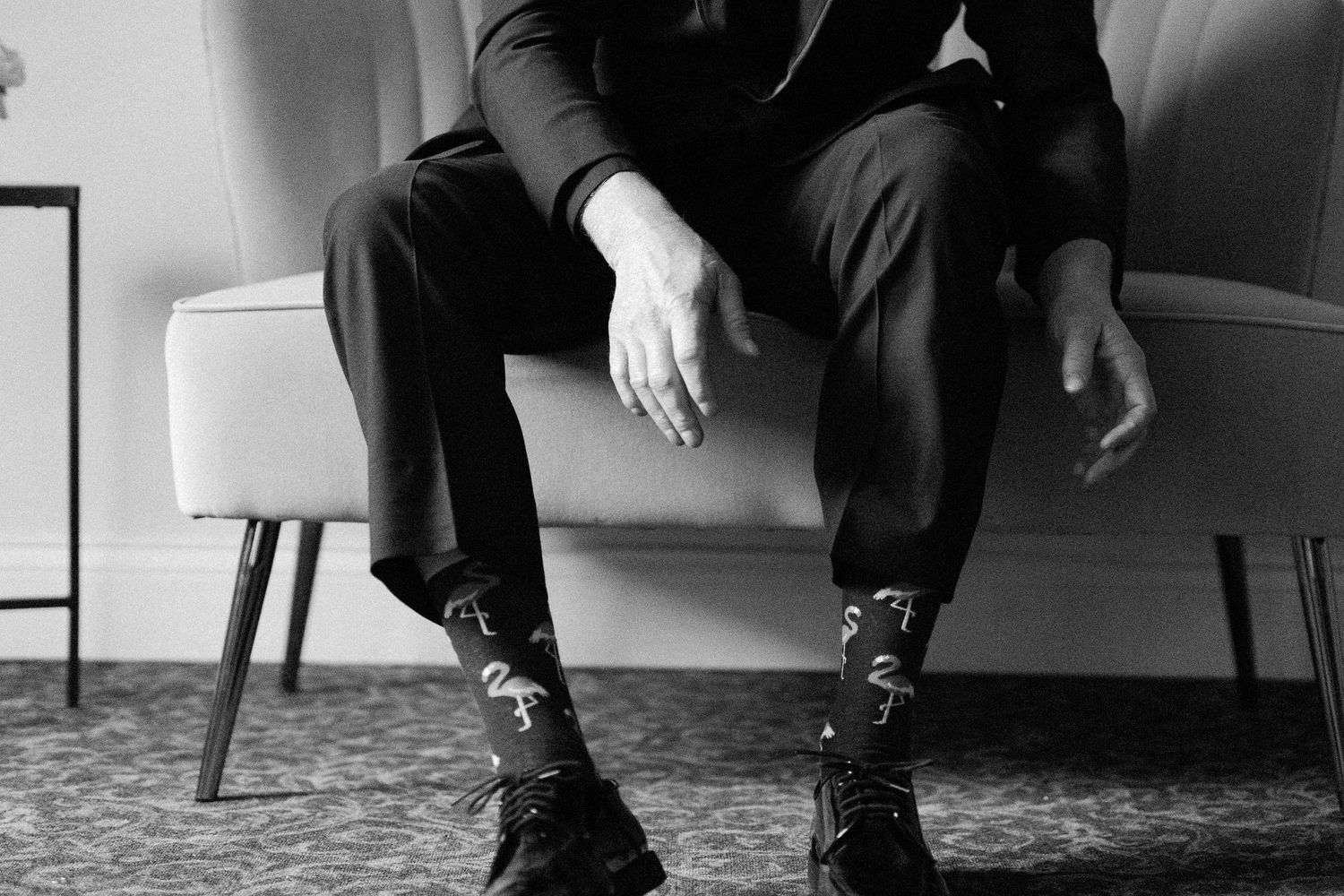 A black and white photo showing legs and feet of people sitting in chairs at a formal event.