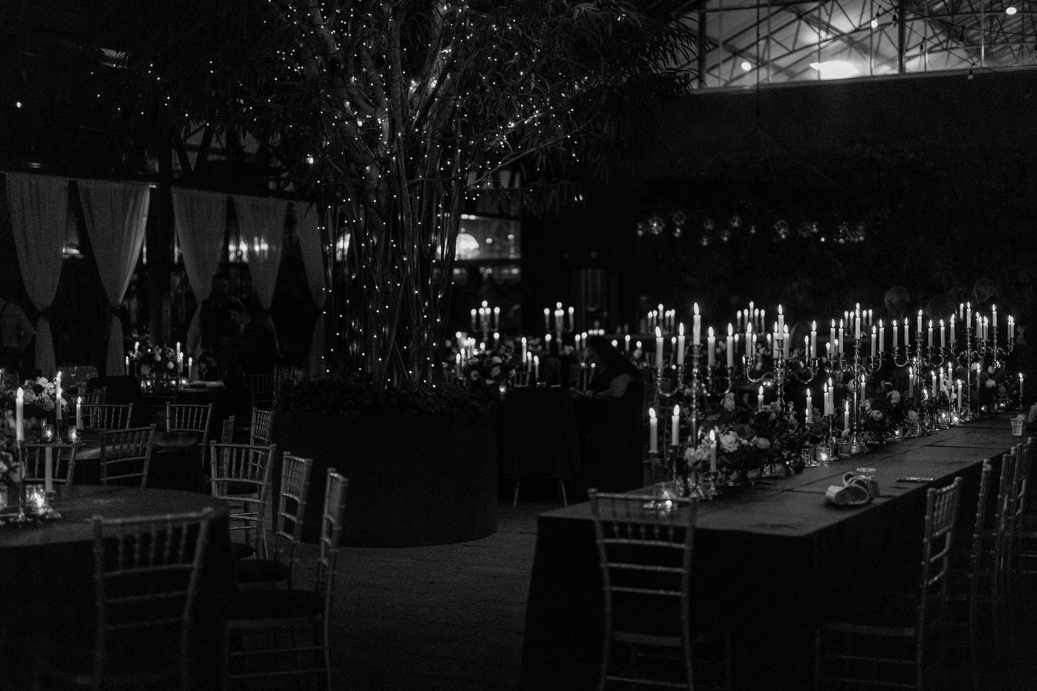 Dramatic reception venue with glowing candles and crystal chandeliers in dark ambiance.