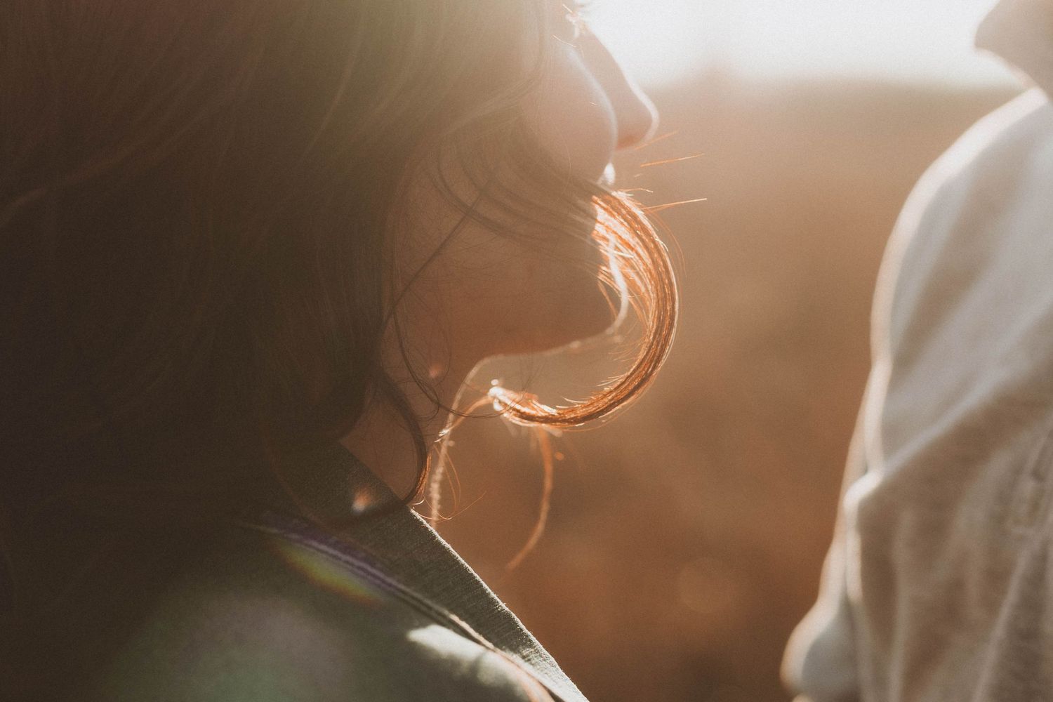 Silhouette of jewelry and earrings backlit by warm golden sunlight.