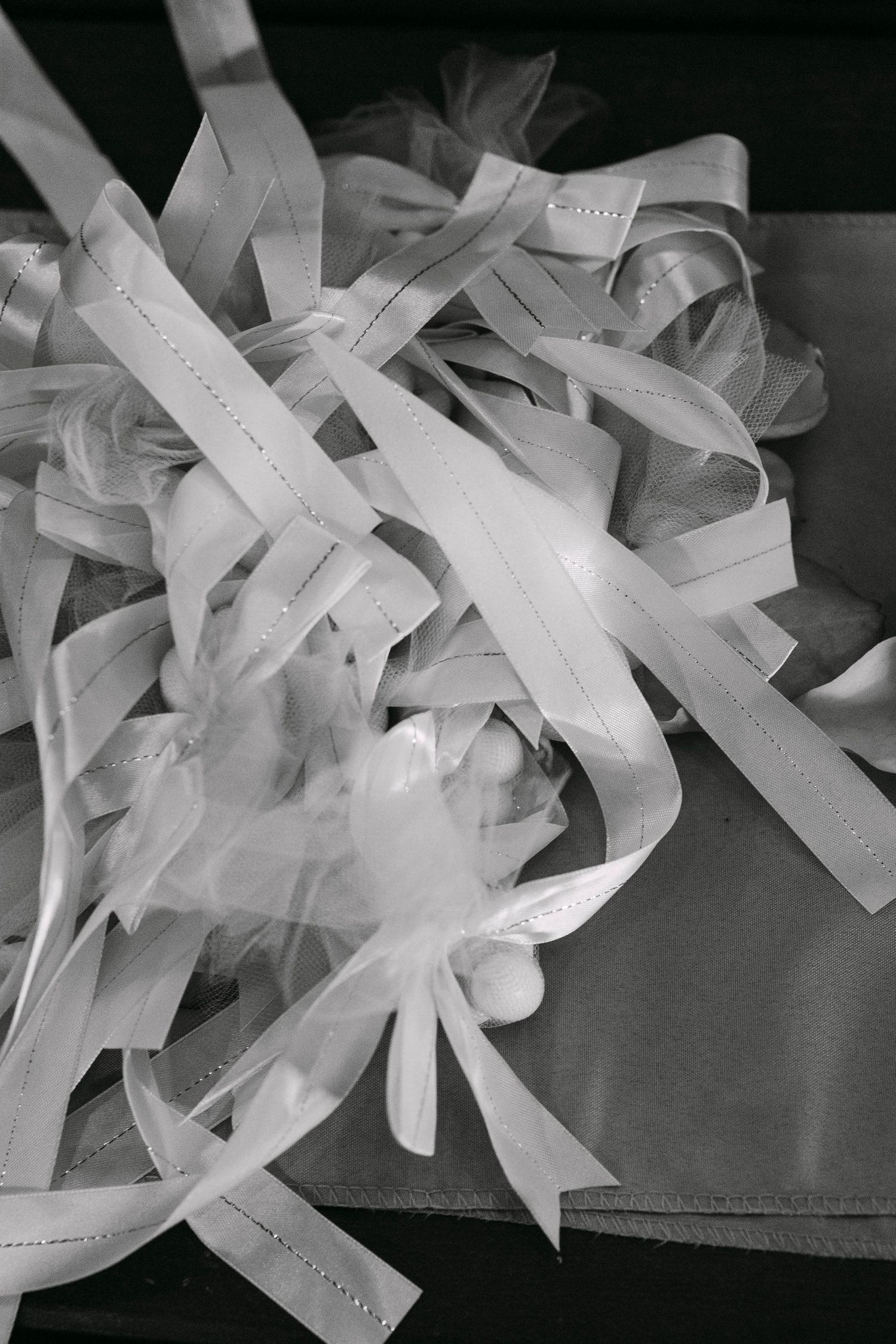 Black and white photo of wedding ribbons and tulle bouquet decorations piled on a gift bag.