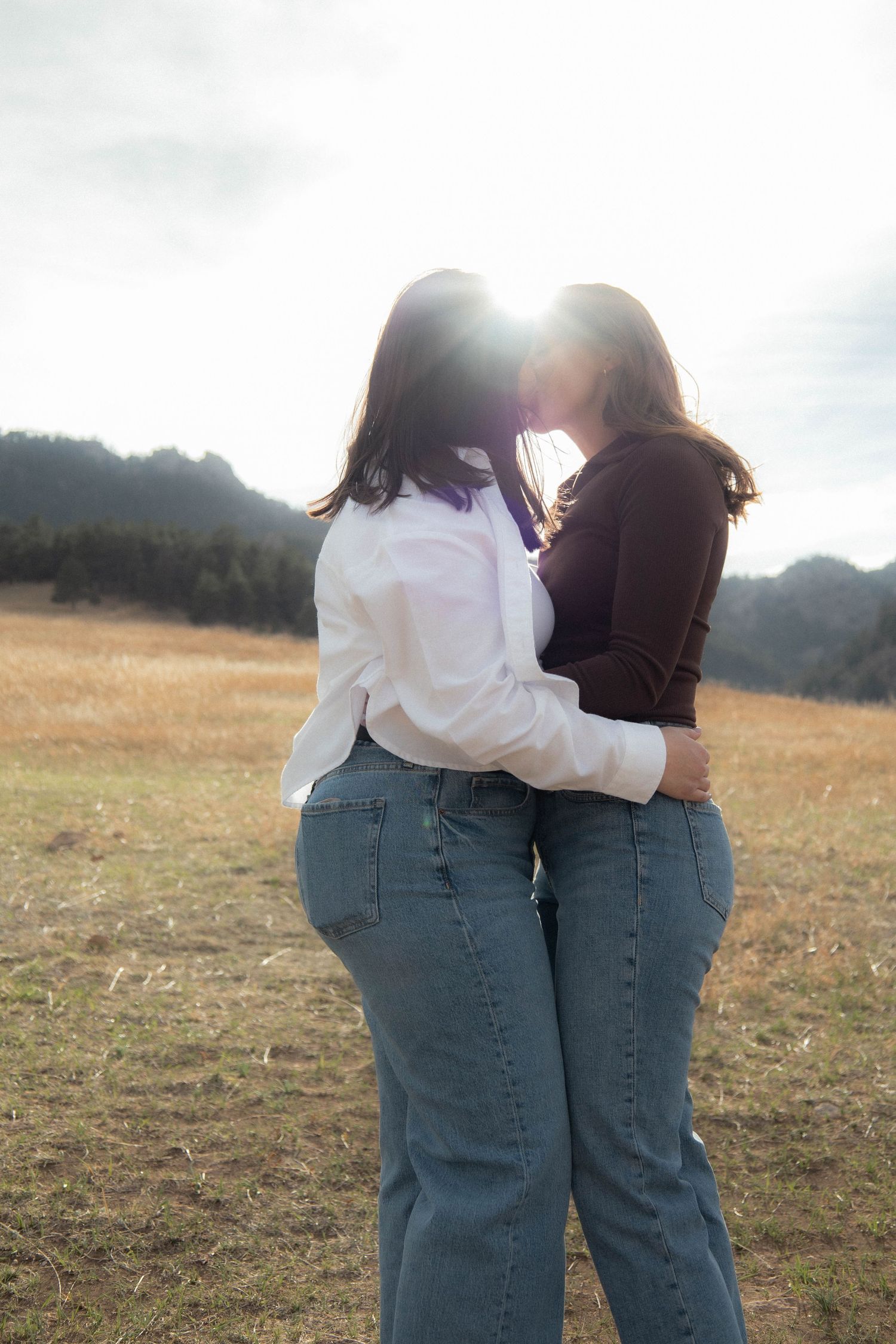 a couple kissing in a green field with the sun right behind them in Boulder, Colorado