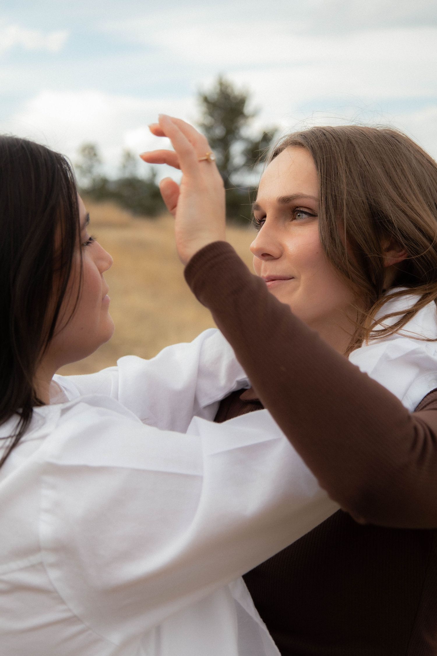 a woman fixing another woman's hair with arms wrapped around one another in Boulder, Colorado