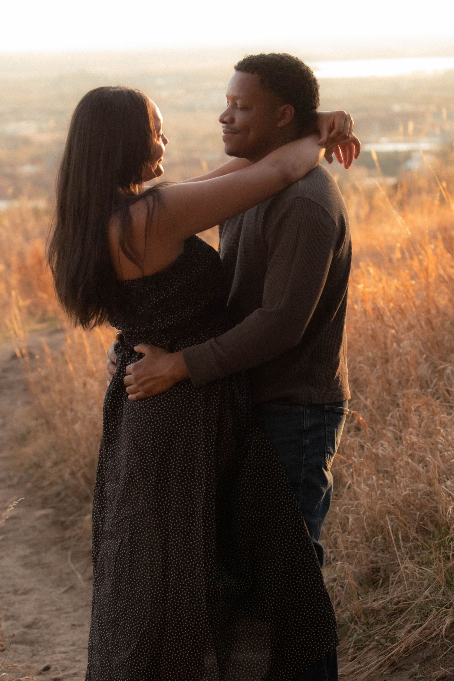 a couple smiling at each other with the woman's arms wrapped around the men's neck in Boulder, Colorado