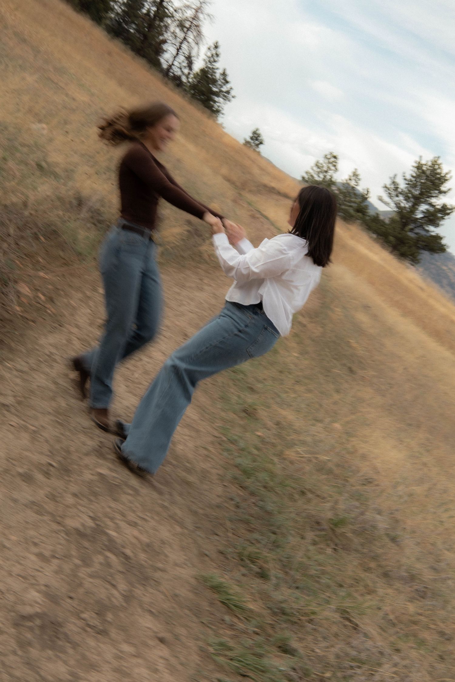a couple holding hands and spinning on a dirty trail with green grass in Boulder, Colorado