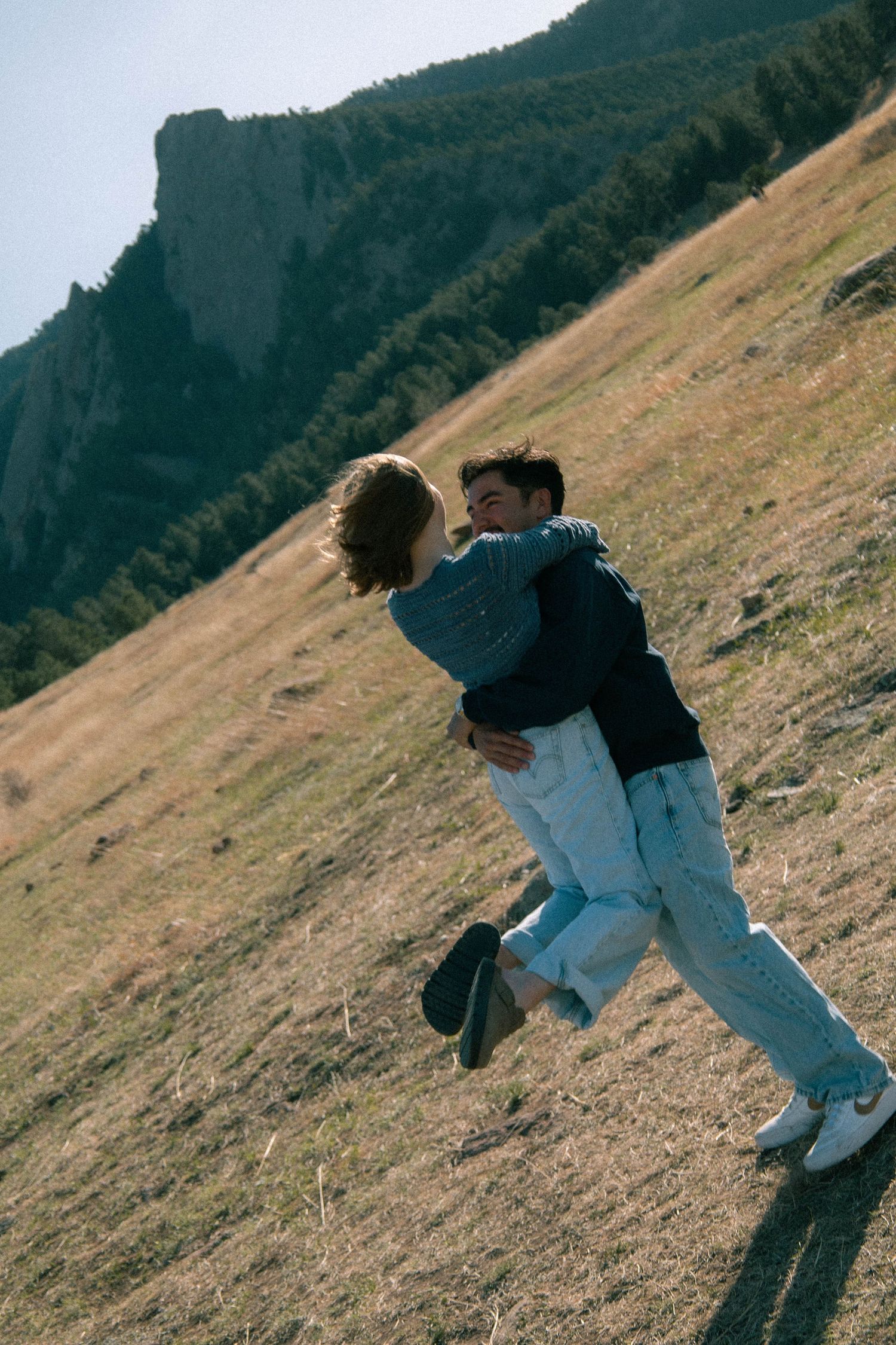 A man spinning a woman in a grassy field with a blue sky in Boulder, Colorado