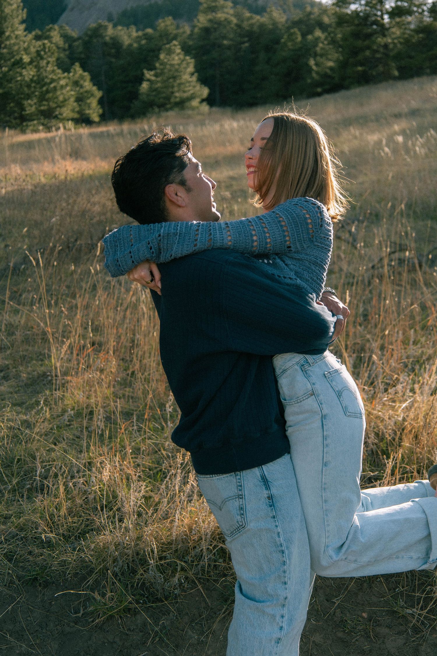 A man spinning a woman with golden light behind them in a grassy field in Boulder, Colorado