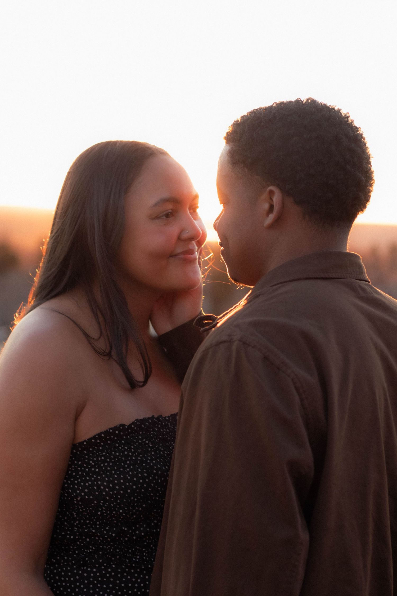 A couple smiling and looking into each other's eyes with golden light behind them in Boulder, Colorado