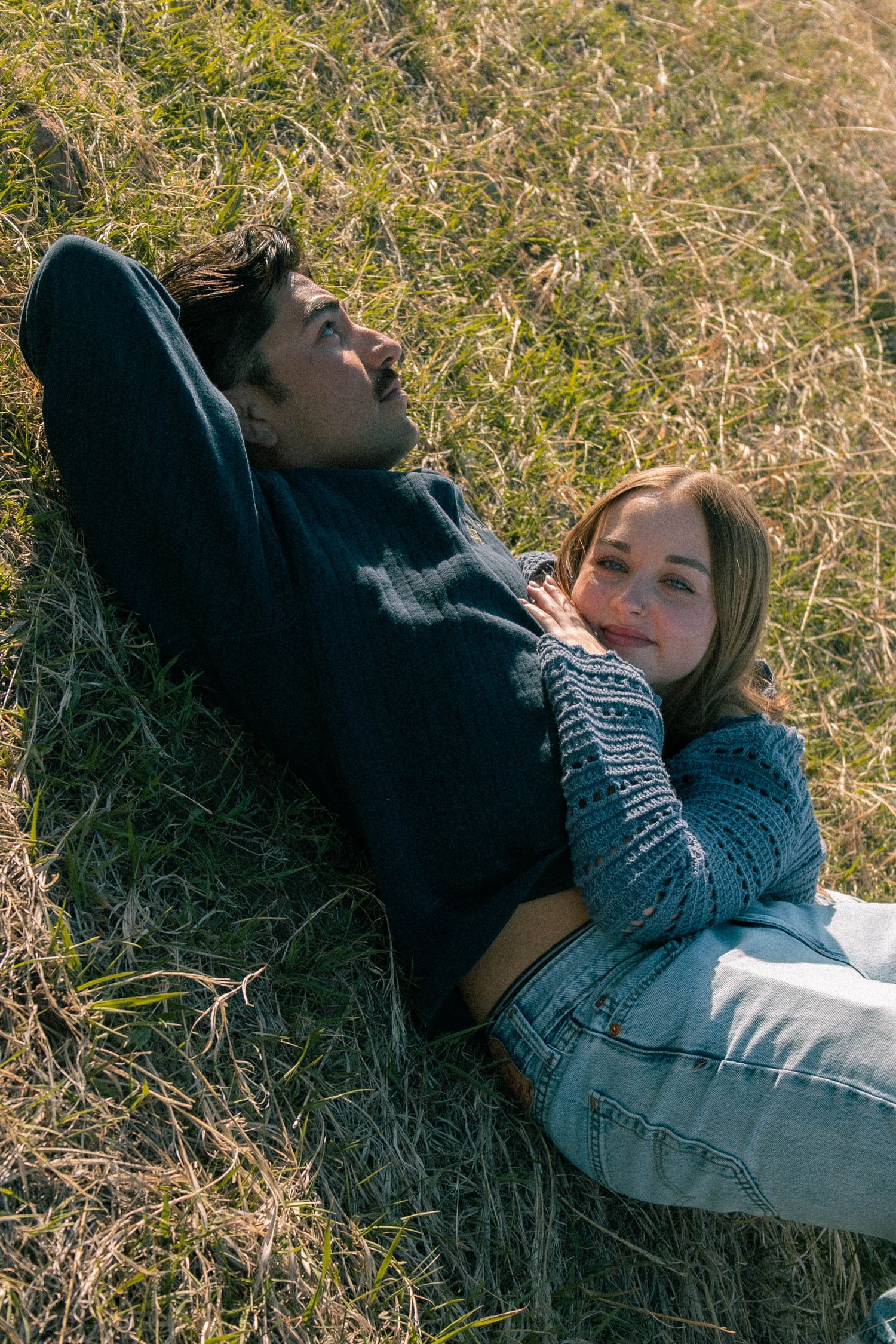 a couple laying on green grass in blue attire in Boulder, Colorado