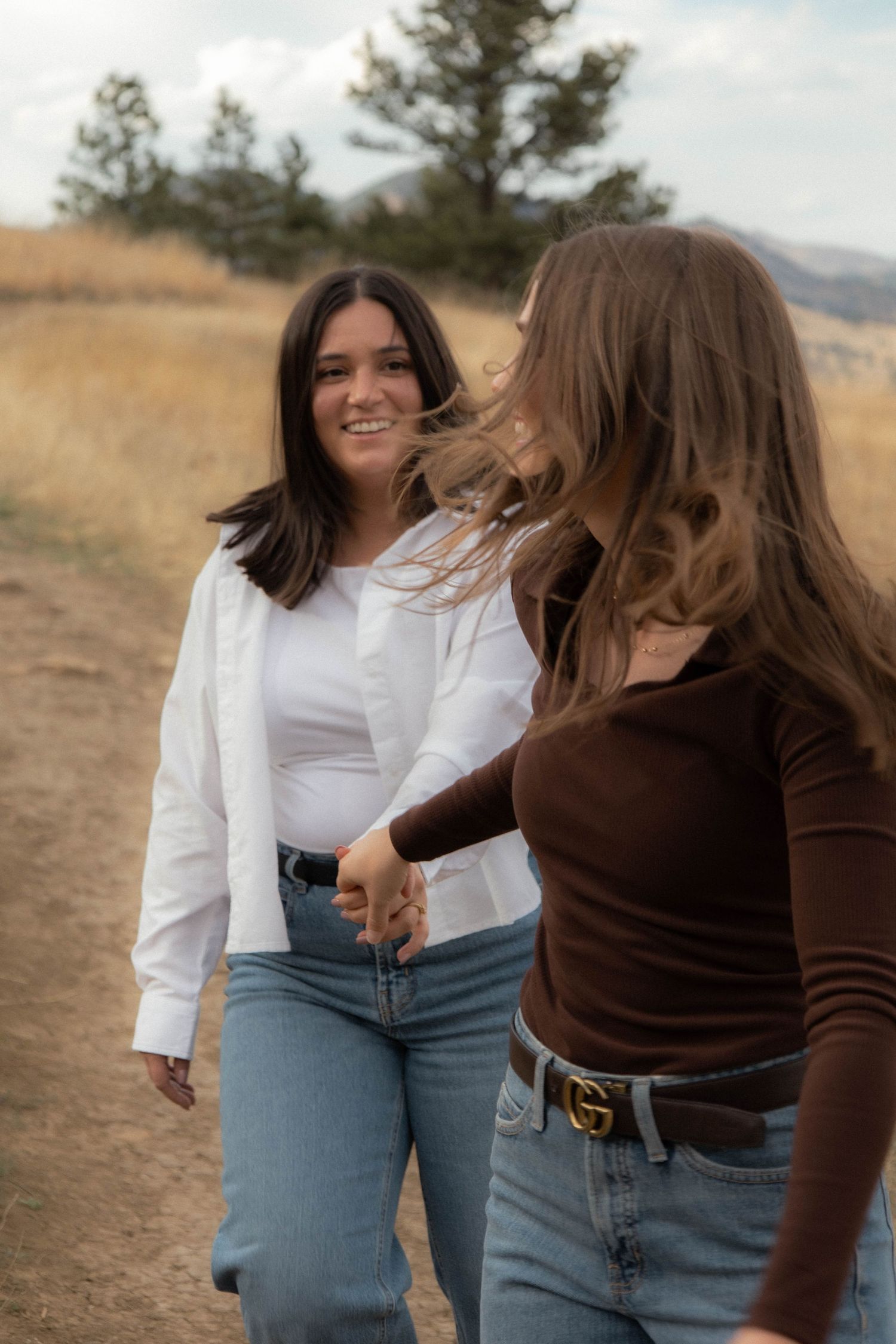 two women walking together one looking back at the other while she smiles in Boulder, Colorado