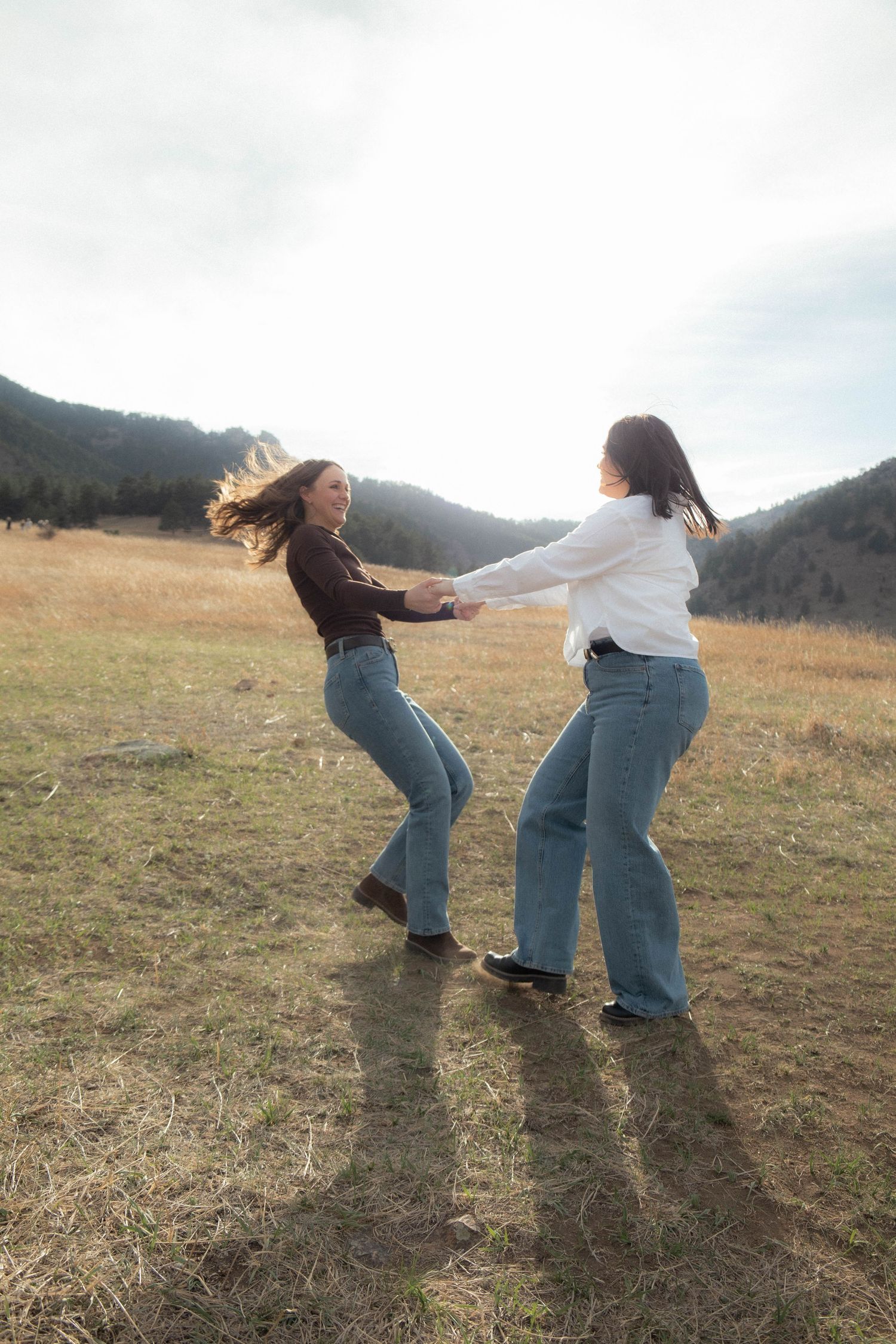 a couple holding hands and spinning in a green field in Boulder, Colorado