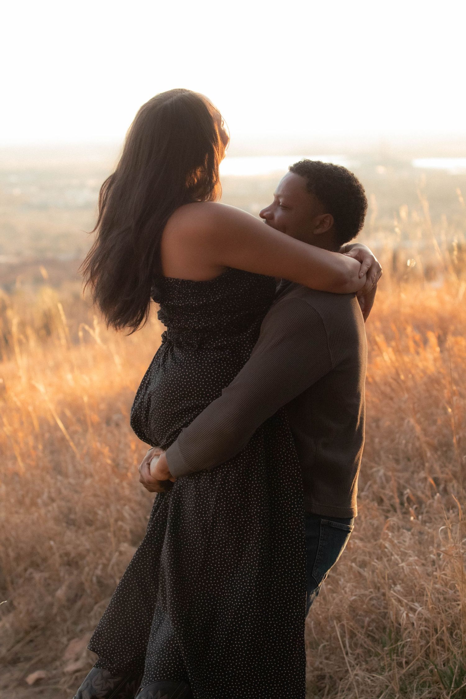 a man lifting a woman and spinning with golden hour light shining behind them in Boulder, Colorado