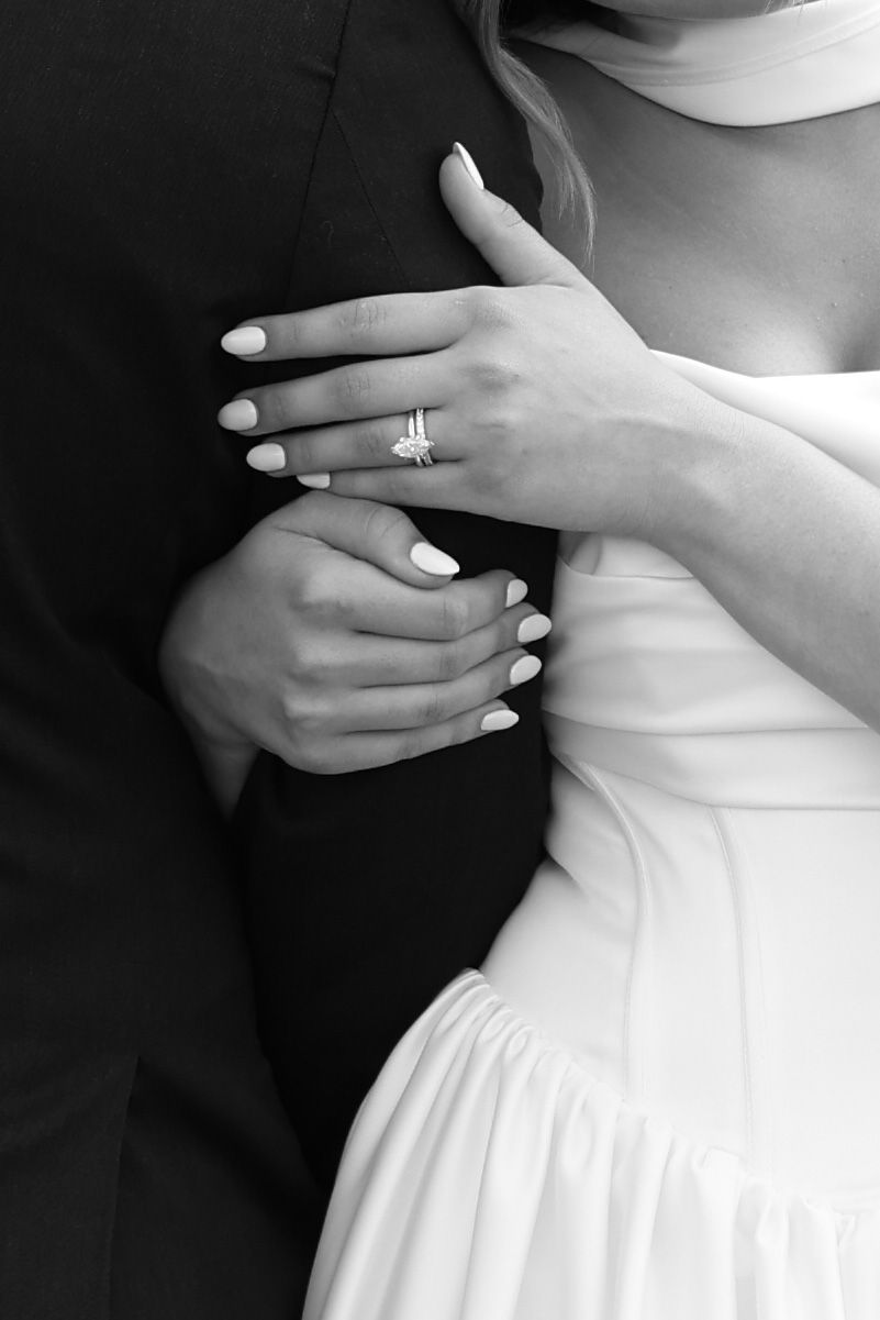 Black and white close-up of bride and groom embracing showing diamond engagement ring.