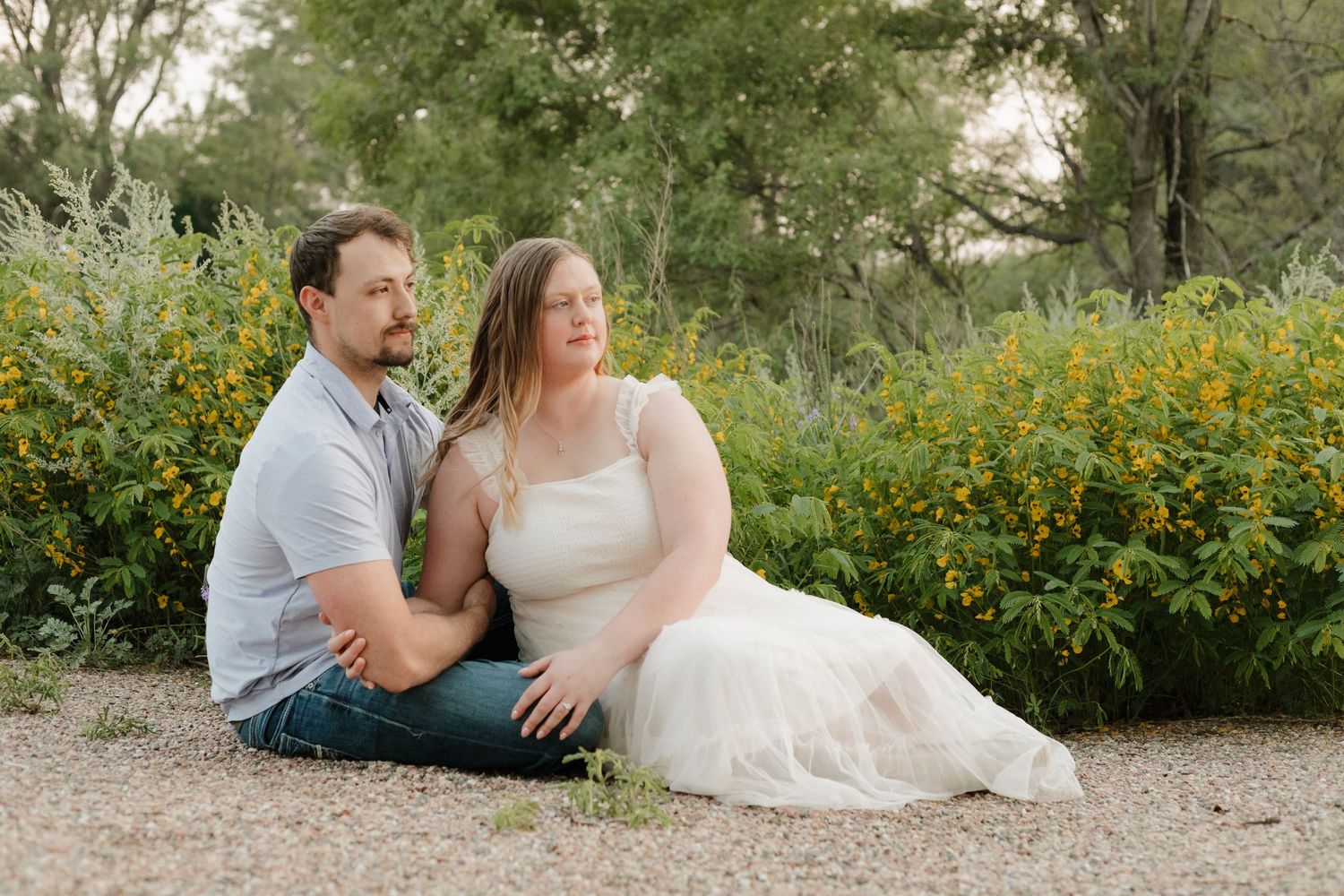 A couple shares an intimate moment among blooming yellow wildflowers in a natural setting.