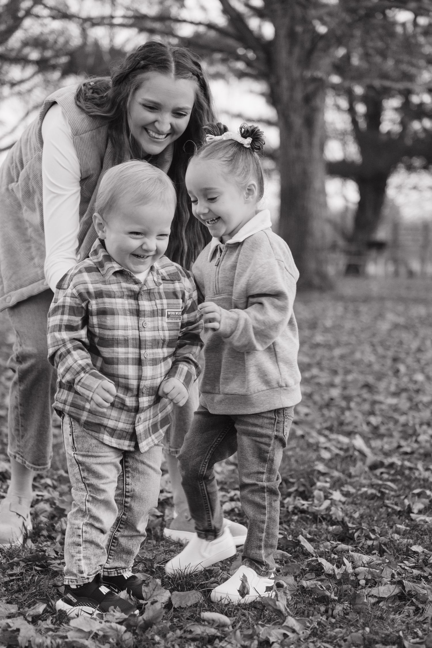 Black and white photos of playful moments in fallen autumn leaves.