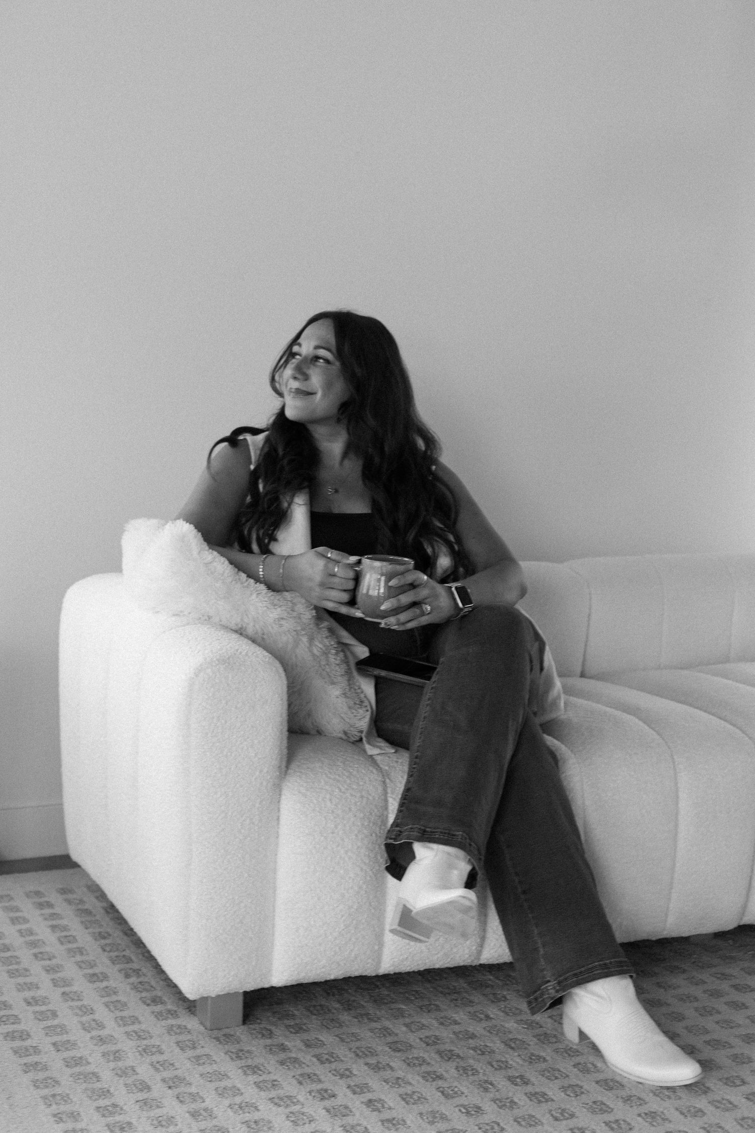 Black and white photo of someone relaxing on a white modern couch.