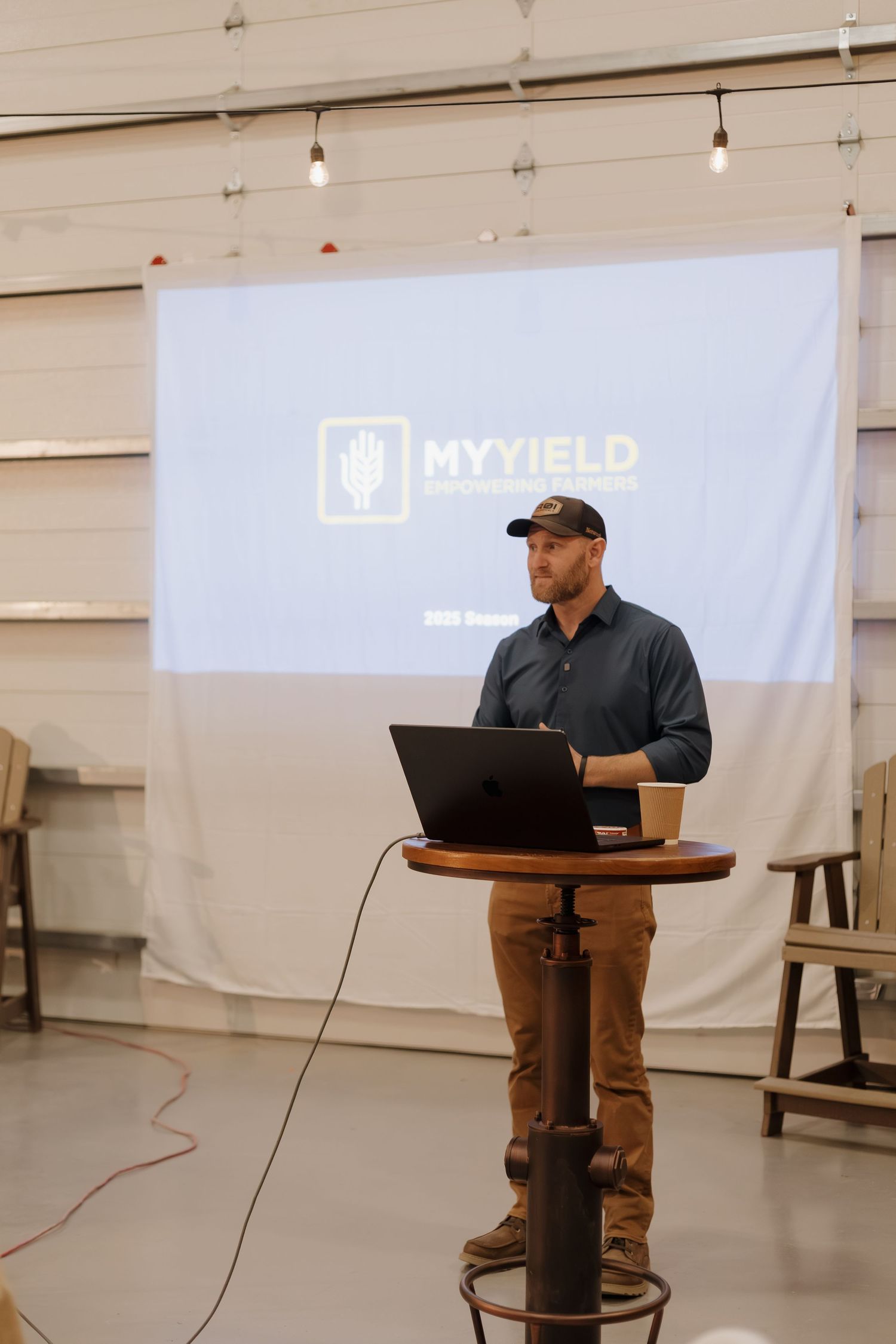 Speaker presents at podium with MyYield logo projected on screen behind them.