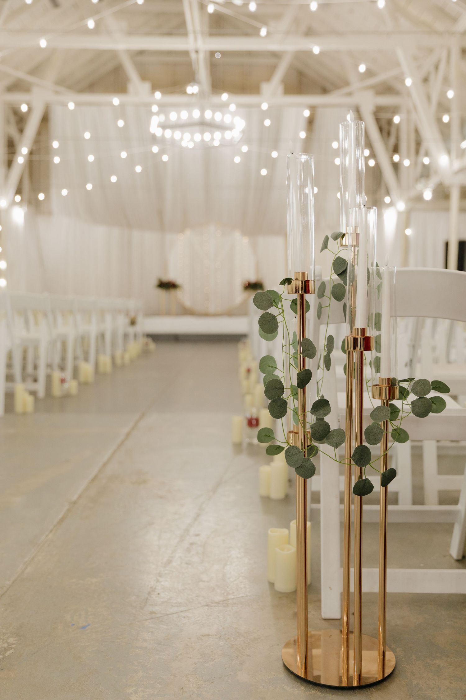 Wedding venue interior with string lights and decorative glass vases lining the aisle at an event and wedding venue East River South Dakota.