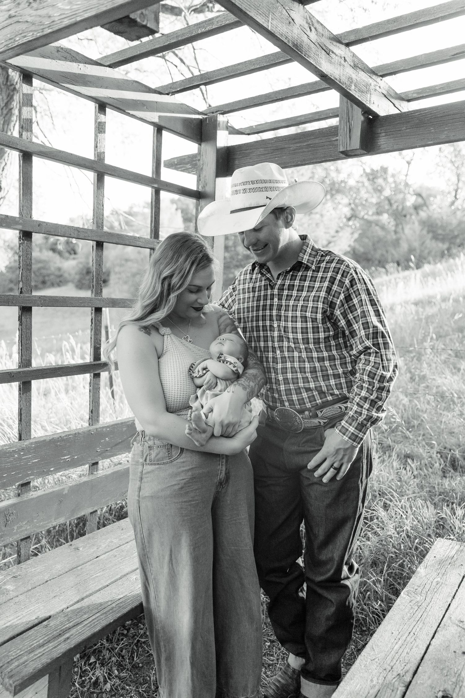 Black and white photo of couple sharing intimate moment on wooden deck.
