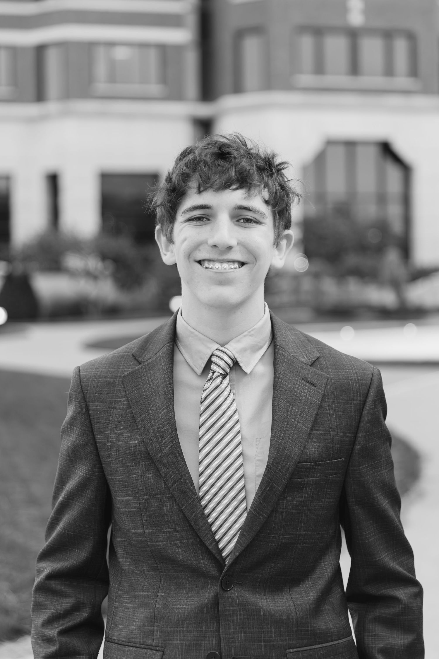 High school senior portrait series showing person in dark suit and striped tie.
