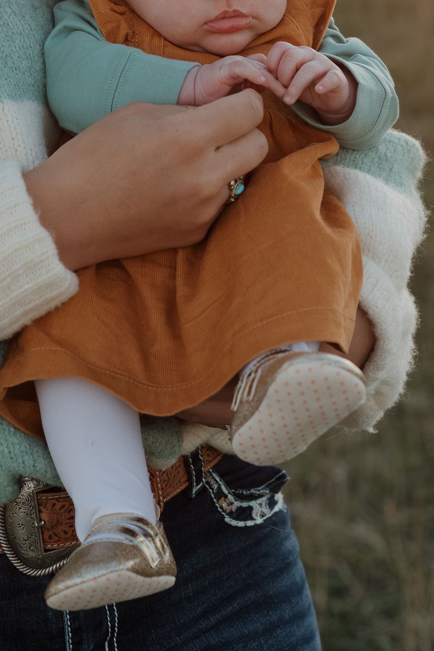 Close-up of brown and white baby shoes with tiny feet wearing white socks.