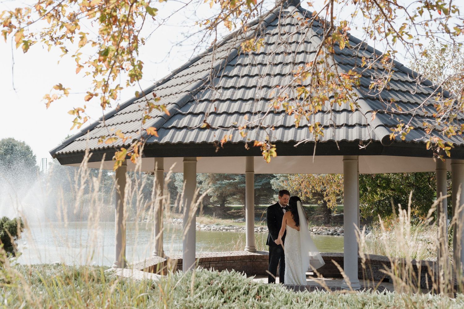 Row of rustic wooden gazebos with thatched roofs in an outdoor garden setting.