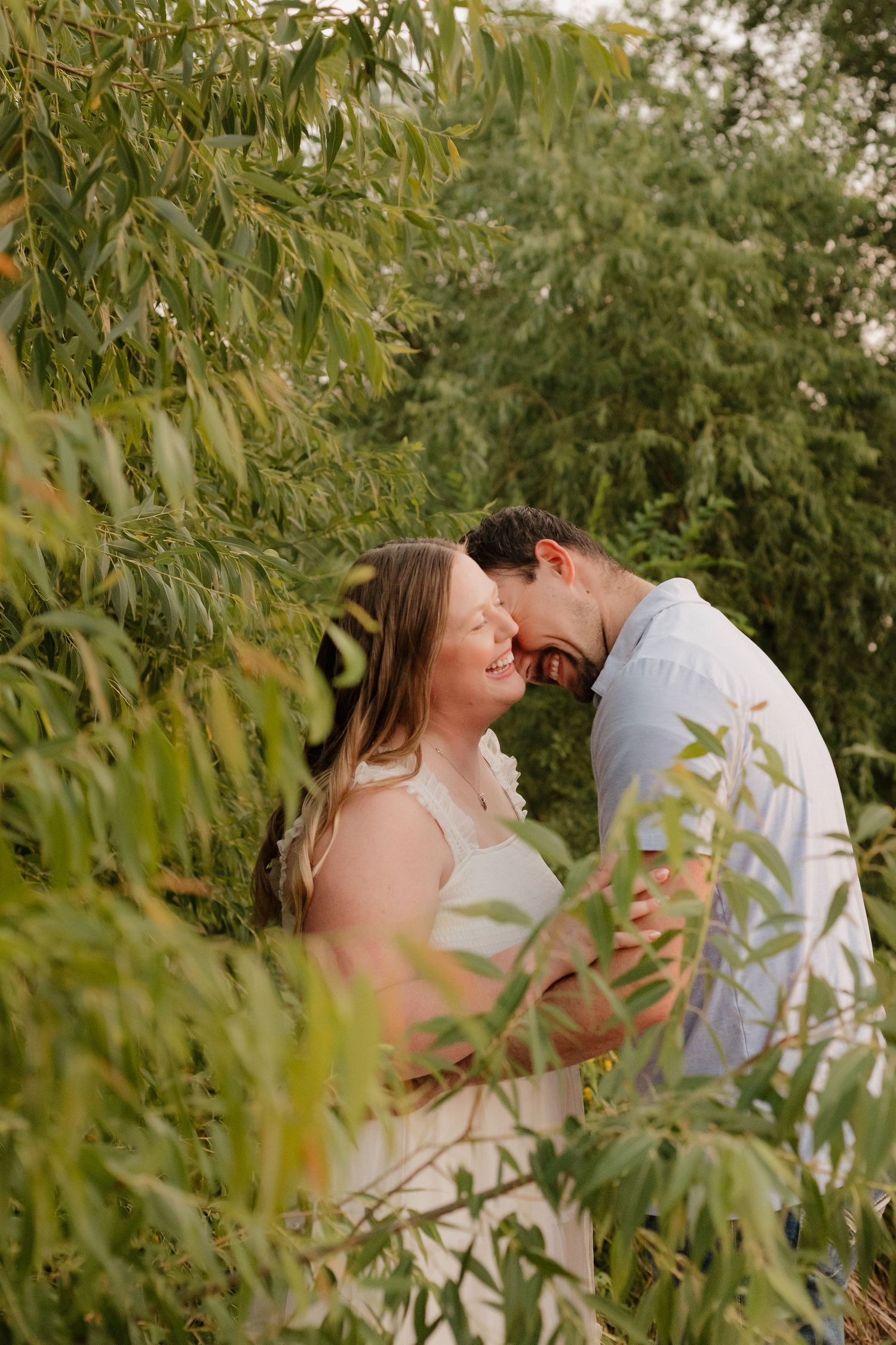 Intimate garden wedding photos among green willow trees at sunset.