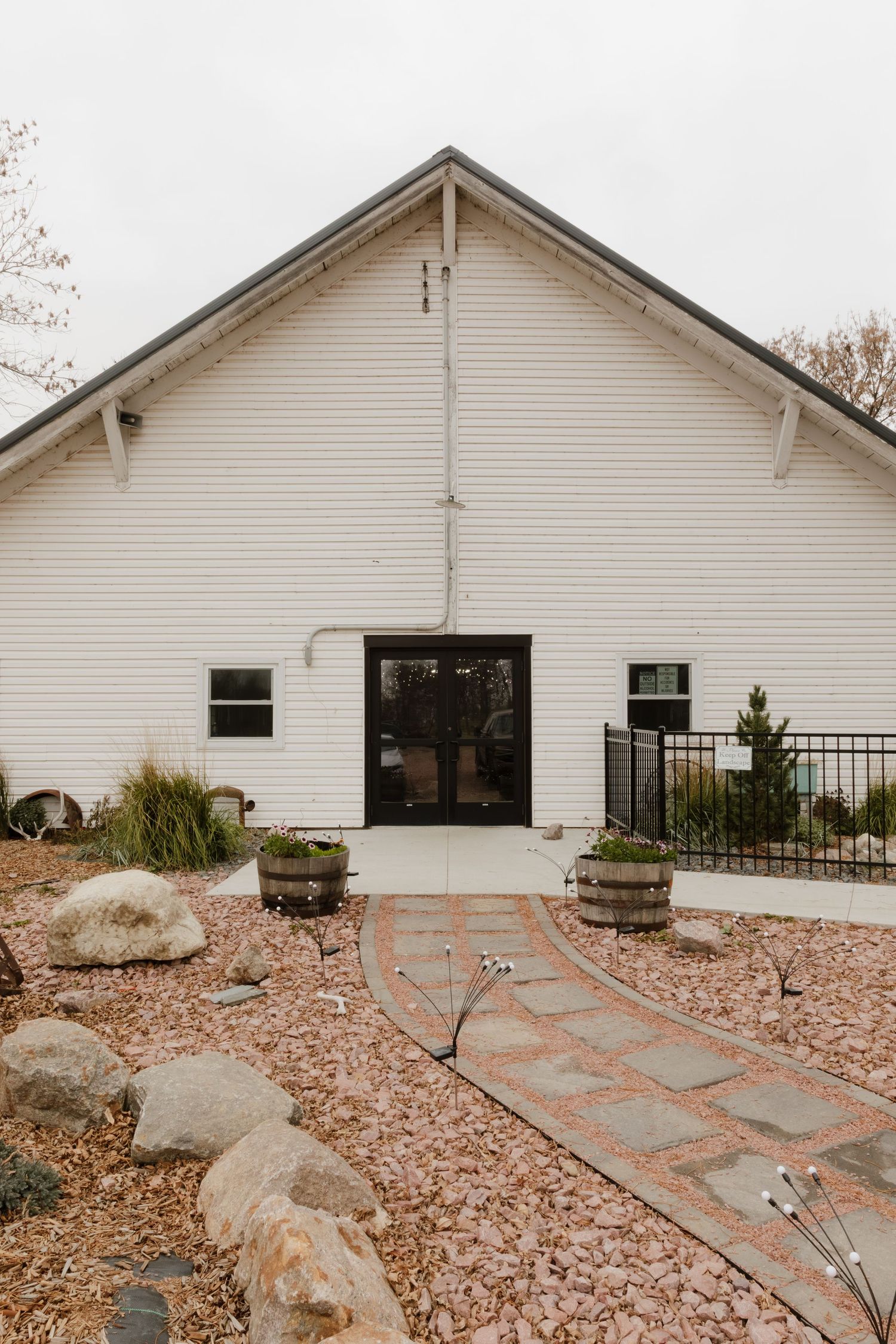 Modern white wedding venue exterior with stone pathway and landscaped garden.