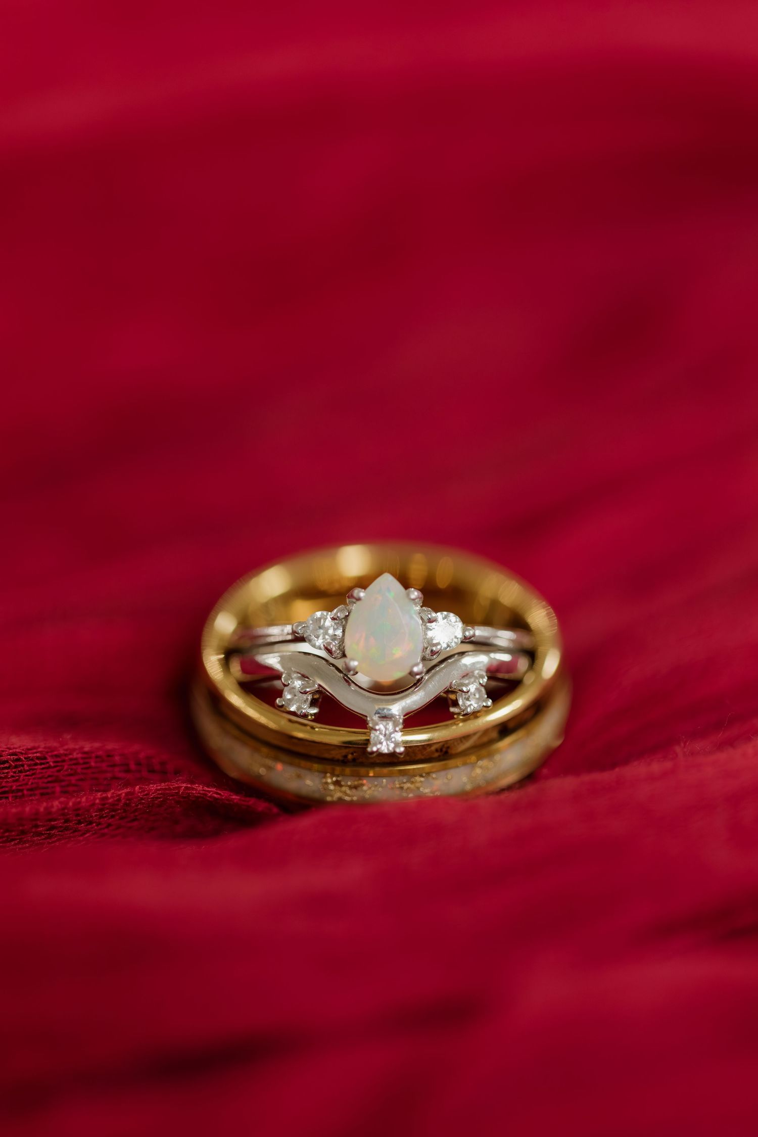 Gold engagement ring with diamond solitaire photographed on red velvet background.