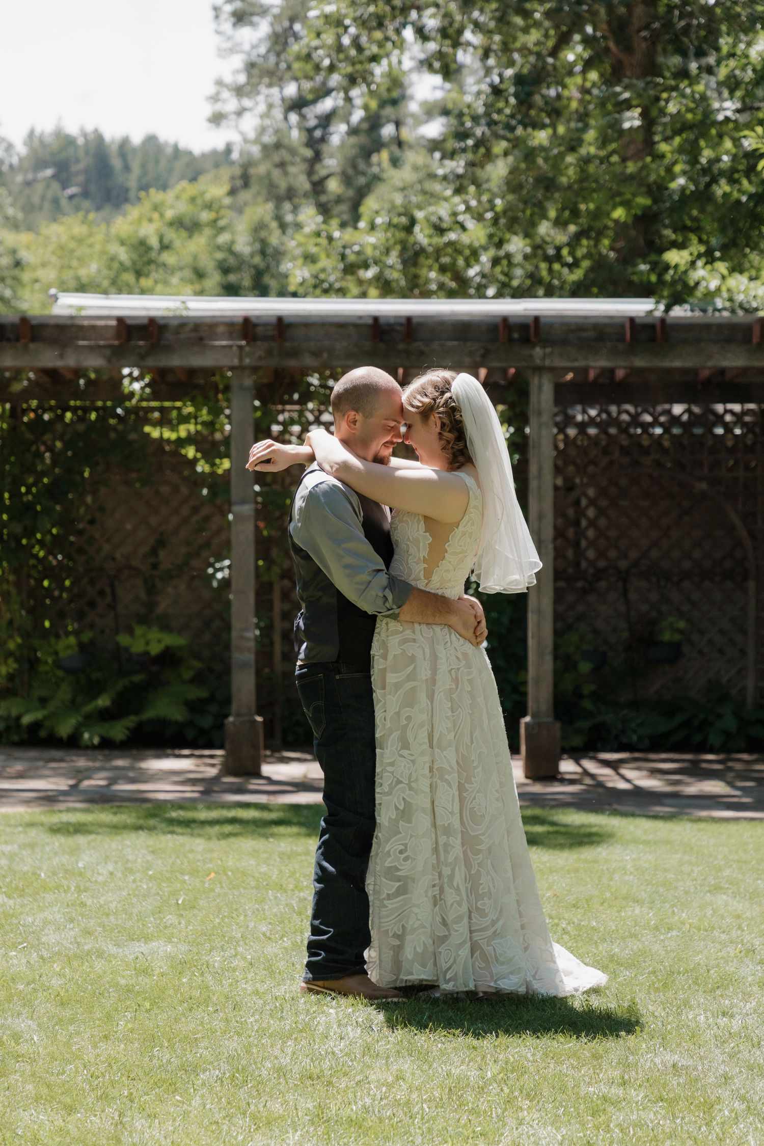 Newlyweds sharing playful dance moves in sunny garden setting.