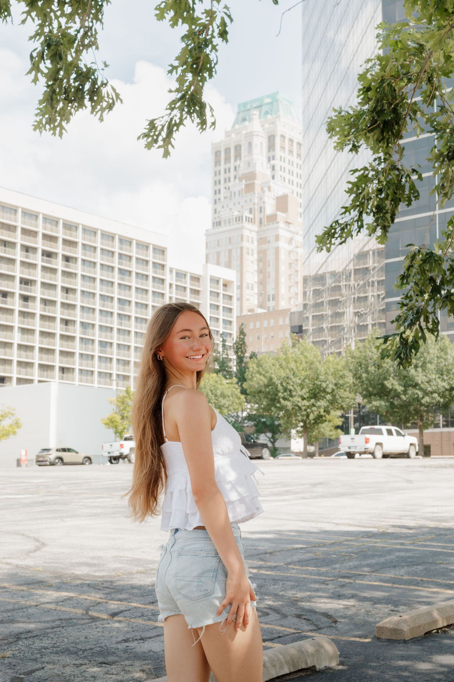 Casual summer street style portrait with downtown buildings and trees in background.