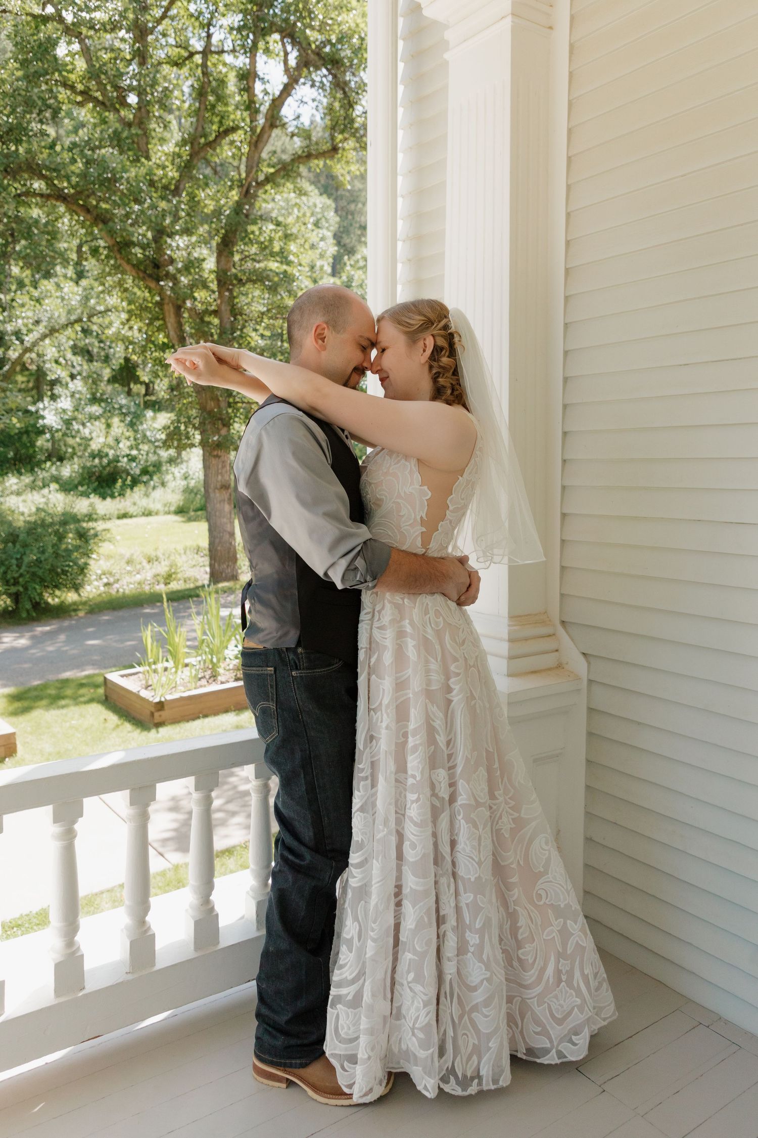 A romantic moment shared on a white porch with rustic details at an elopement wedding at Ruby's Garden, Spearfish, South Dakota.