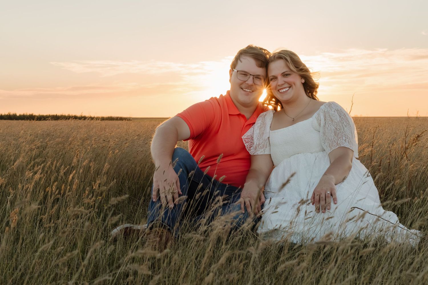 A couple shares a romantic moment in a golden wheat field during sunset.