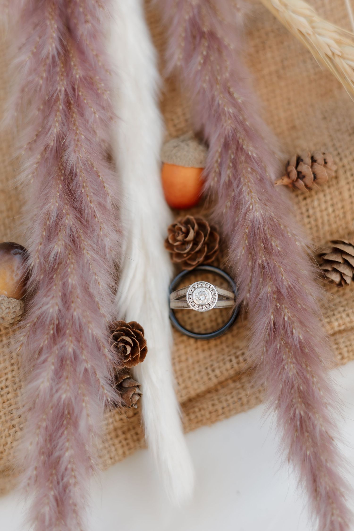 Decorative dried pampas grass and pine cones arranged on burlap create a rustic wedding detail.