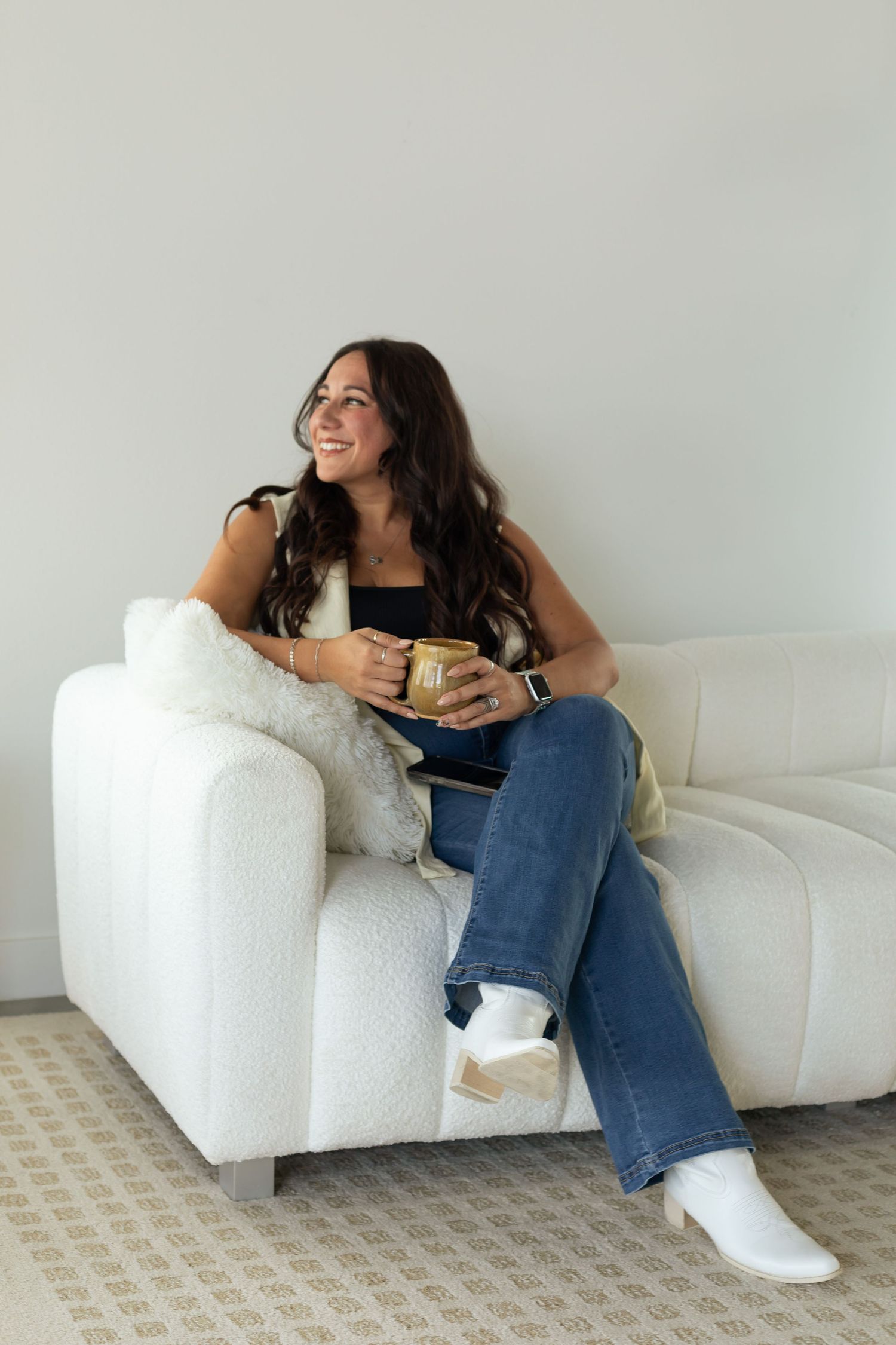 Lifestyle photos of someone relaxing on white couch with drink in casual attire.