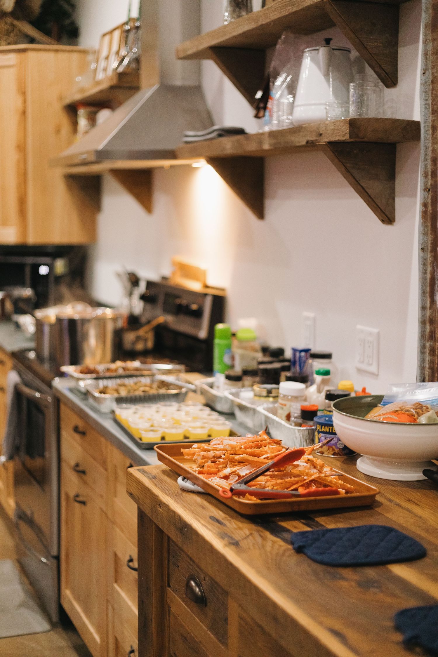 Wooden kitchen counter with various dishes and appetizers laid out in a buffet style setup.