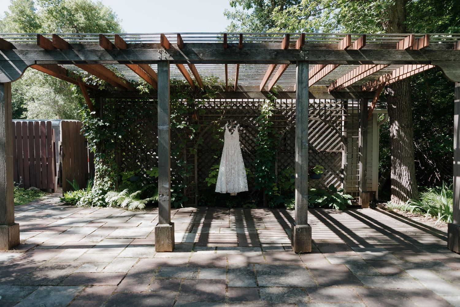 Panoramic view of wooden pergola and garden pathway in summer setting.
